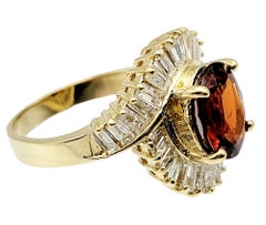 Oval Cut Garnet and Baguette Diamond Swirl Halo Cocktail Ring in 14 Karat Gold