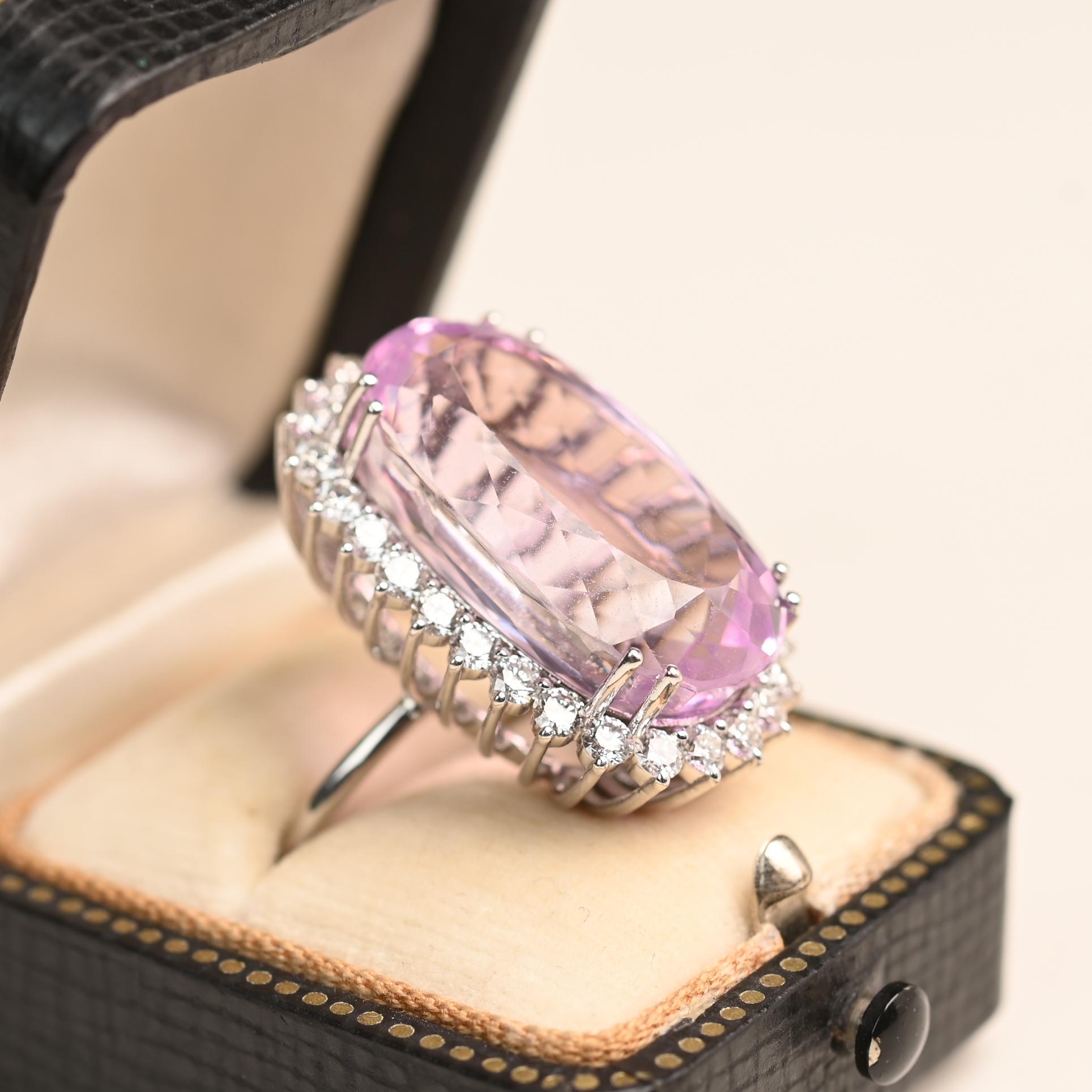 Bague de cocktail vintage centrée sur une kunzite ovale allongée pesant environ 29,20 carats. La pierre précieuse rose-lavande est fixée dans une monture à deux griffes et entourée d'une grappe de diamants à griffes partagées d'un poids total