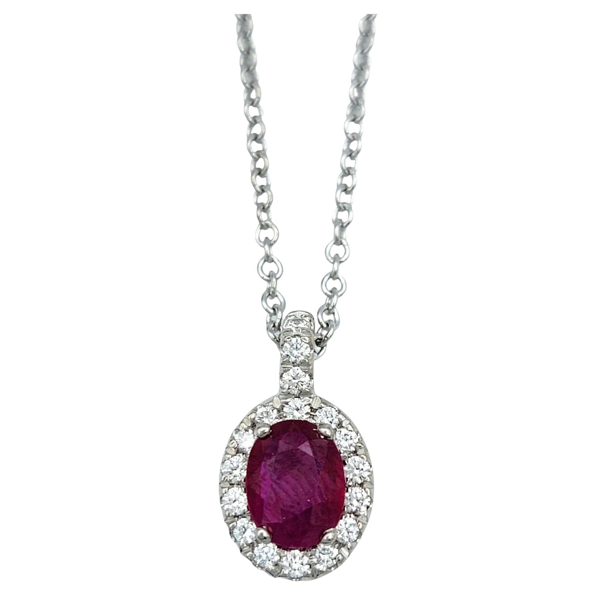 Eleva tu elegancia con este exquisito collar colgante de rubí natural de talla ovalada y halo de diamantes en oro blanco de 18 quilates. Esta impresionante pieza presenta un vibrante rubí de talla oval, famoso por su rico y cautivador tono rojo.