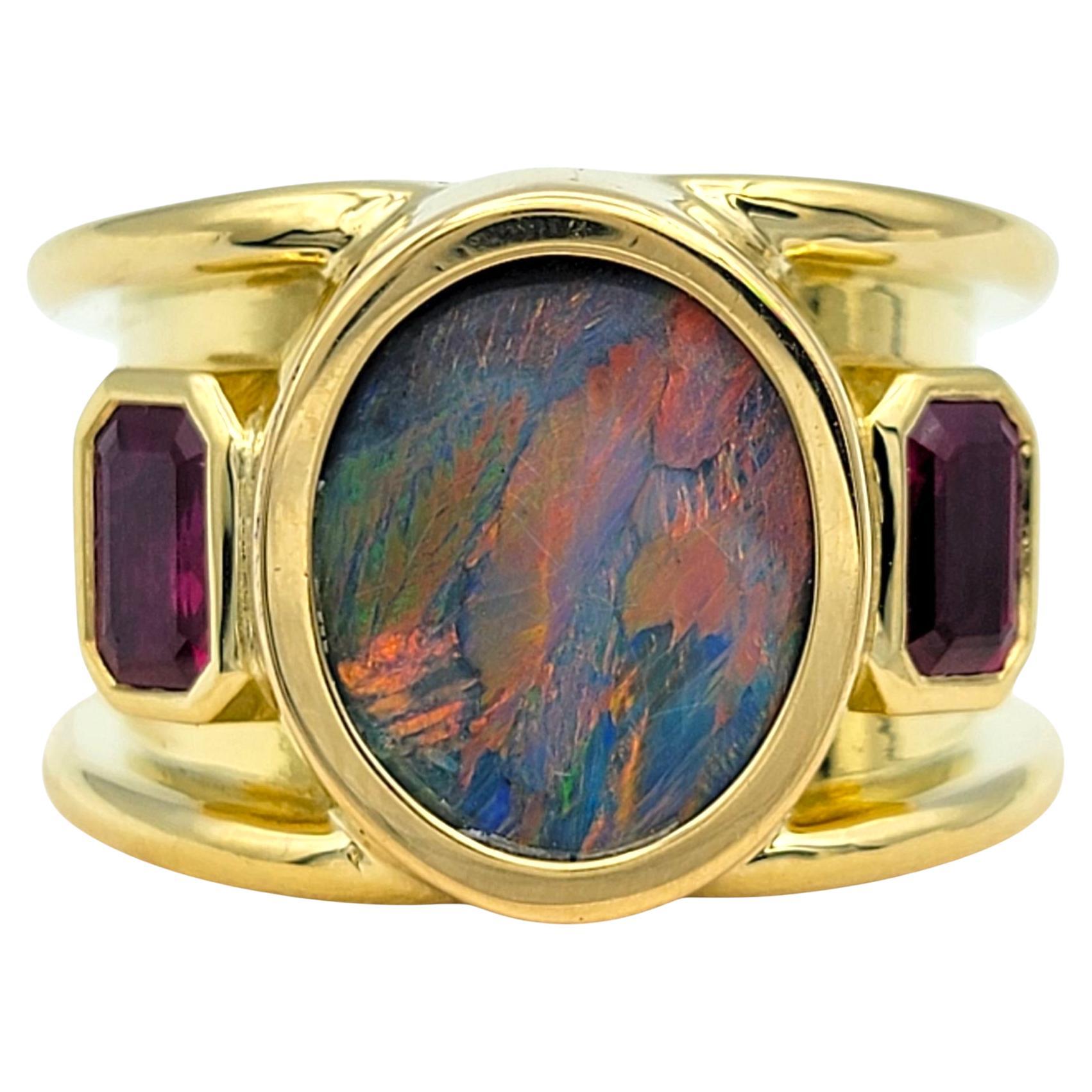 Ring Size: 7.5

This bold and artistic ring captures the drama of natural gemstones in a luxurious, sculptural form. At its center is a vivid oval-cut opal with a kaleidoscope of fiery hues that shimmer with every movement. Framed by radiant-cut