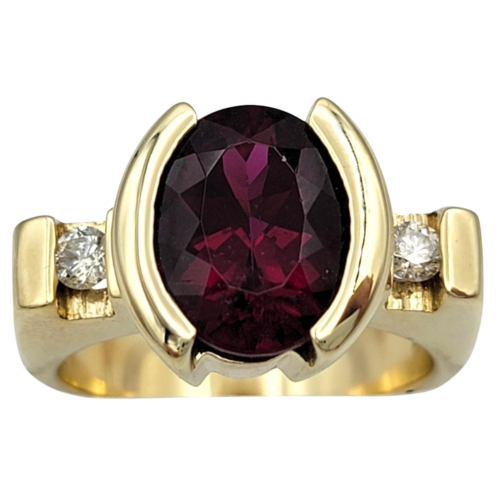 Taille de lla bague : 6

Un vif grenat rhodolite de 3,69 carats de taille ovale est la vedette de cette bague audacieuse et raffinée, sertie dans une riche monture en or jaune 14 carats. La teinte rouge profond du grenat est mise en valeur par le