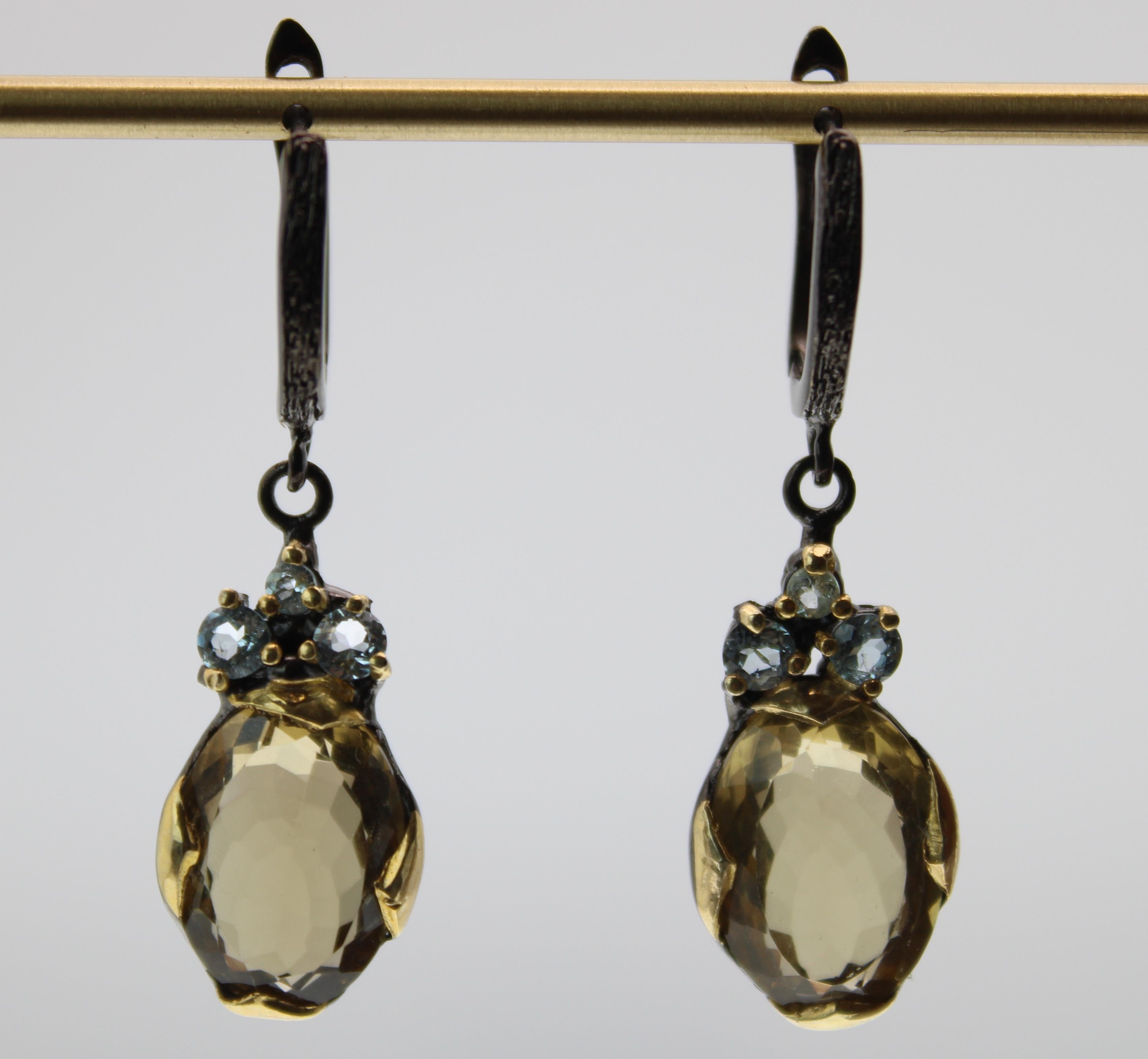Multifaceted rose cut oval yellow lemon quartz earrings with three blue topaz round stones. These earrings are cast and set in 14K gold plating and black rhodium over sterling silver. When held to the light you can see the shine and luster of these
