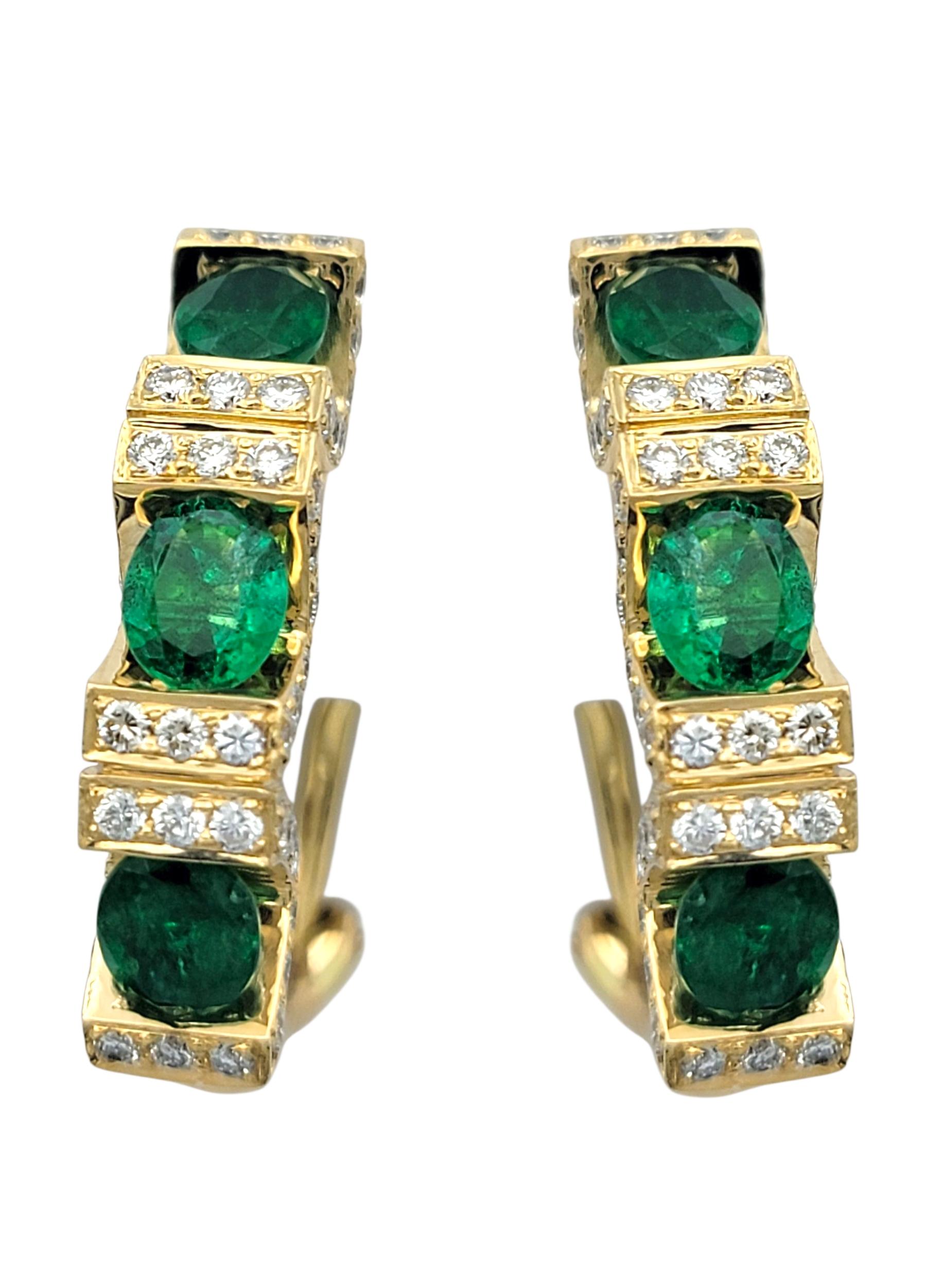 Estos lujosos pendientes presentan vibrantes esmeraldas de Zambia de talla ovalada, cada una de ellas resplandeciente con un profundo tono verde que captura la riqueza del berilo natural. Engarzadas verticalmente en un clásico diseño de aro en J,
