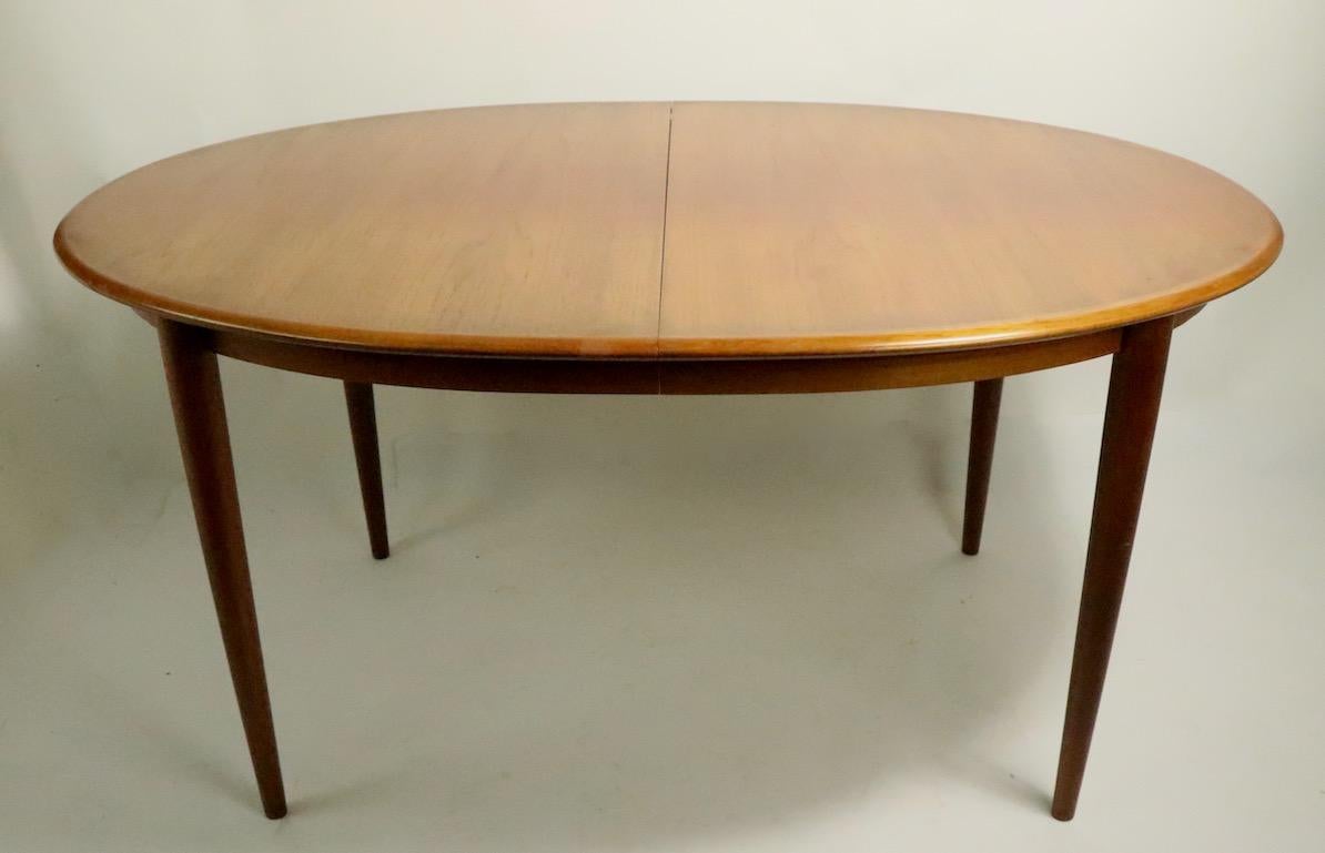 Large oval Danish Modern teak dining table which opens to accept two leaves (19 5/8 inch W each ) The table is in very good original condition, the top shows some tonal variation on the top surface, please see images. Table W without leaves 59 x 98