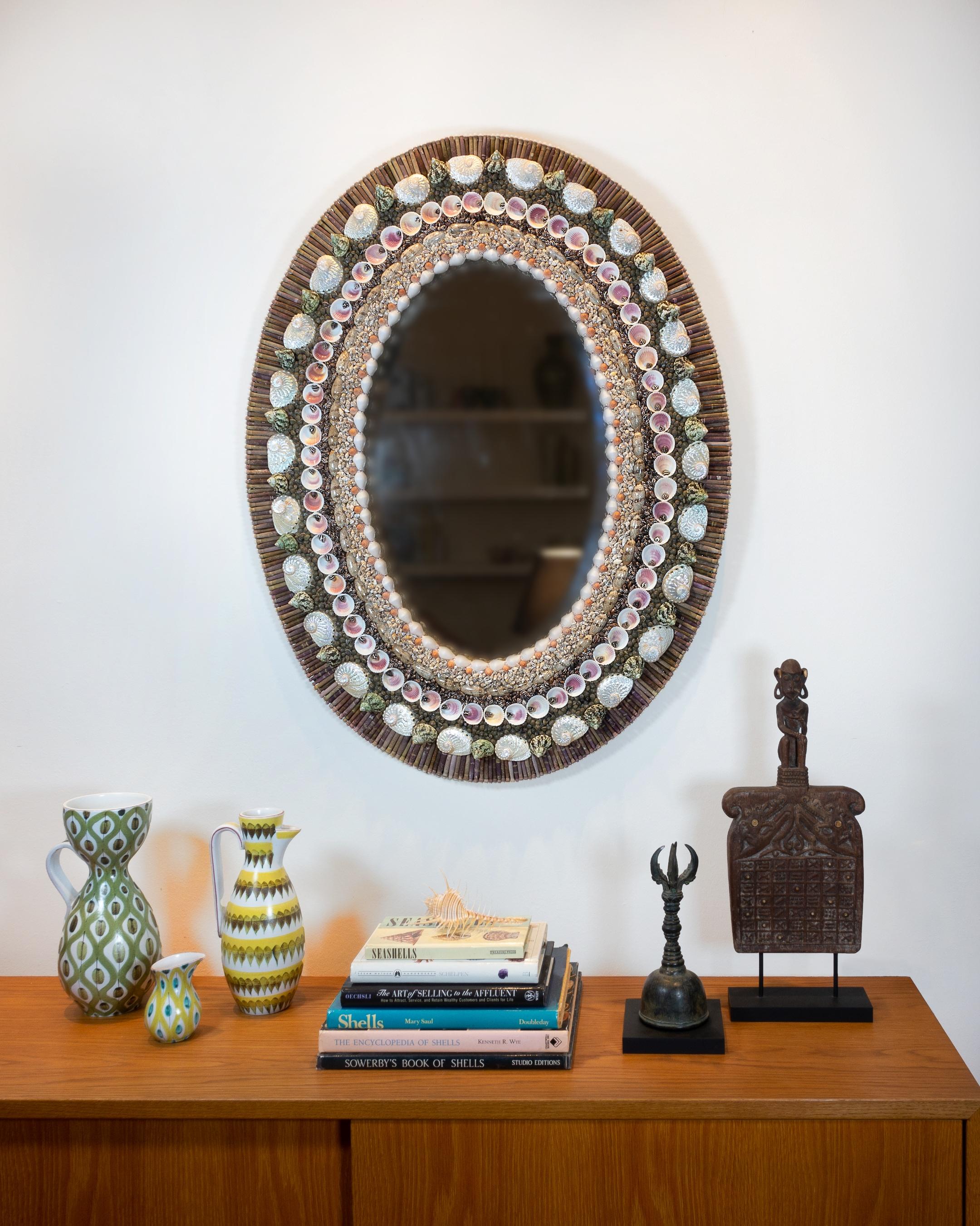 Oval Decisions – unique shell mirror by Shellman Scandinavia in Sweden.

A beautiful oval shell mirror with vintage facet cut glass from early 1900s meticulously decorated throughout with urchin spines, polished abalones and shells like olives,