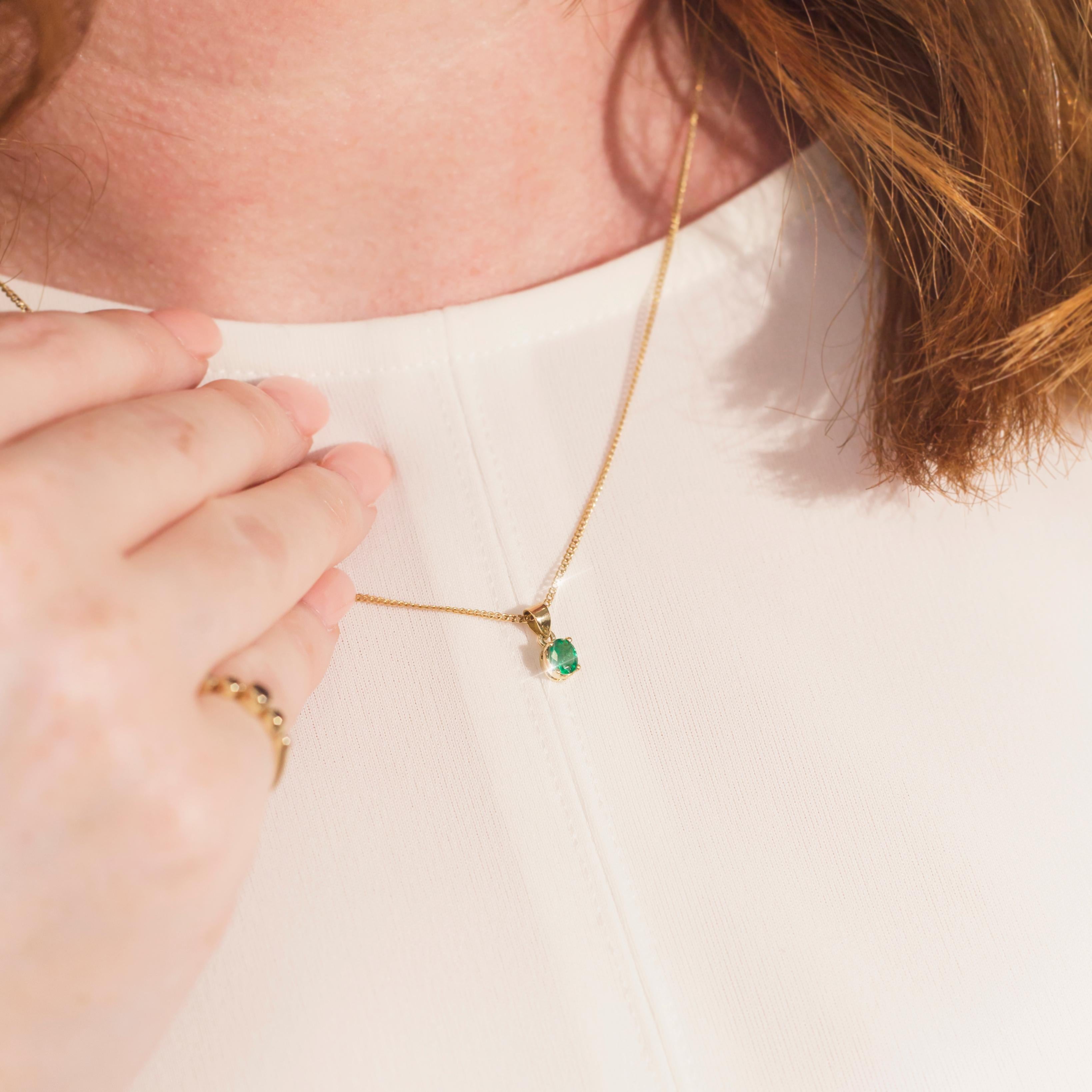 Lovingly crafted in 18 carat yellow gold, this petite vintage pendant and chain shows that simplicity and elegance can go hand-in-hand. The charming natural green oval cut emerald, resting in a lovely four claw setting, radiates gently, evoking