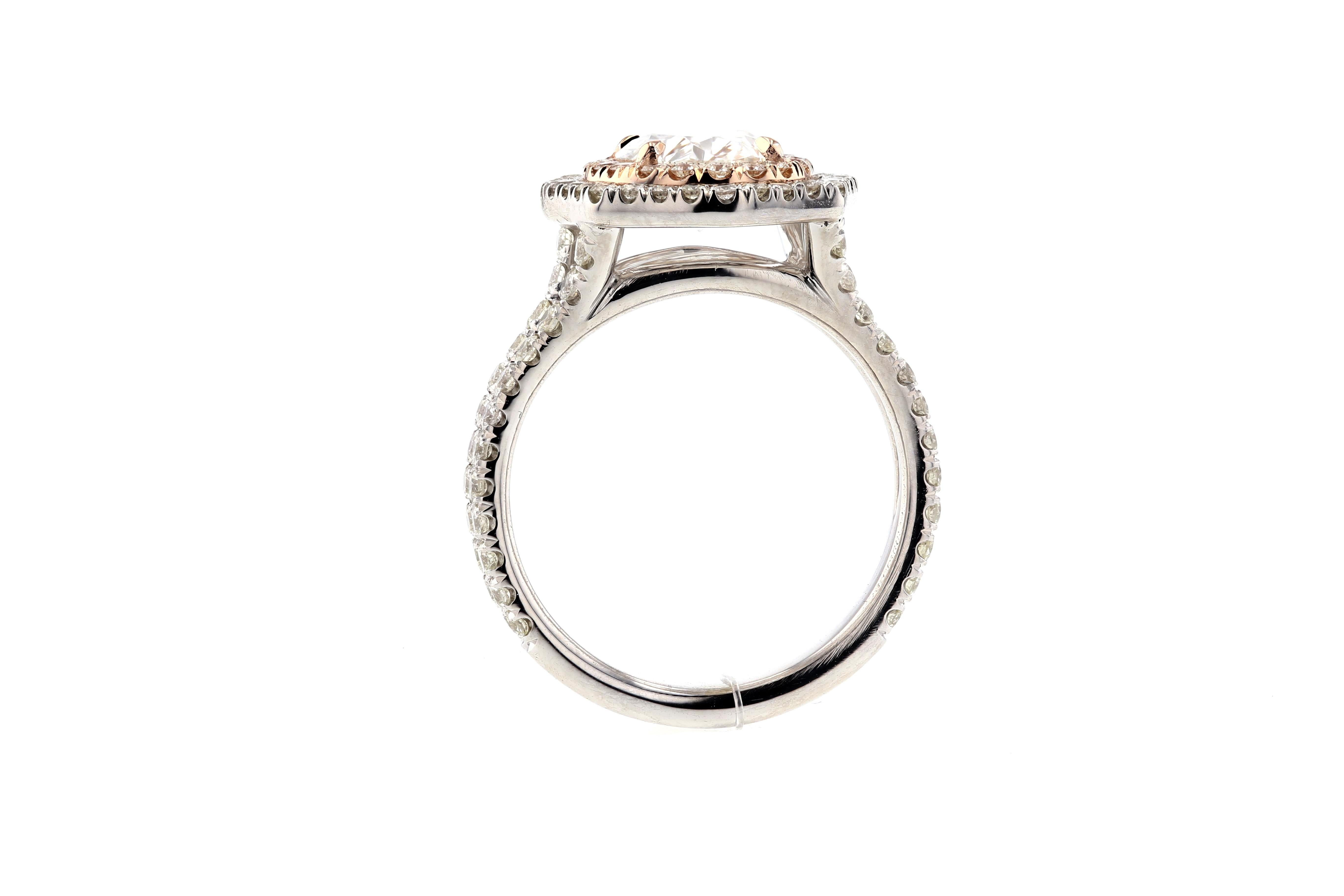 This custom oval diamond engagement ring features a double diamond halo. One halo is set in white gold and the other in rose gold, giving it a unique two tone look. The look is made complete with a split shank covered in diamond pave and an