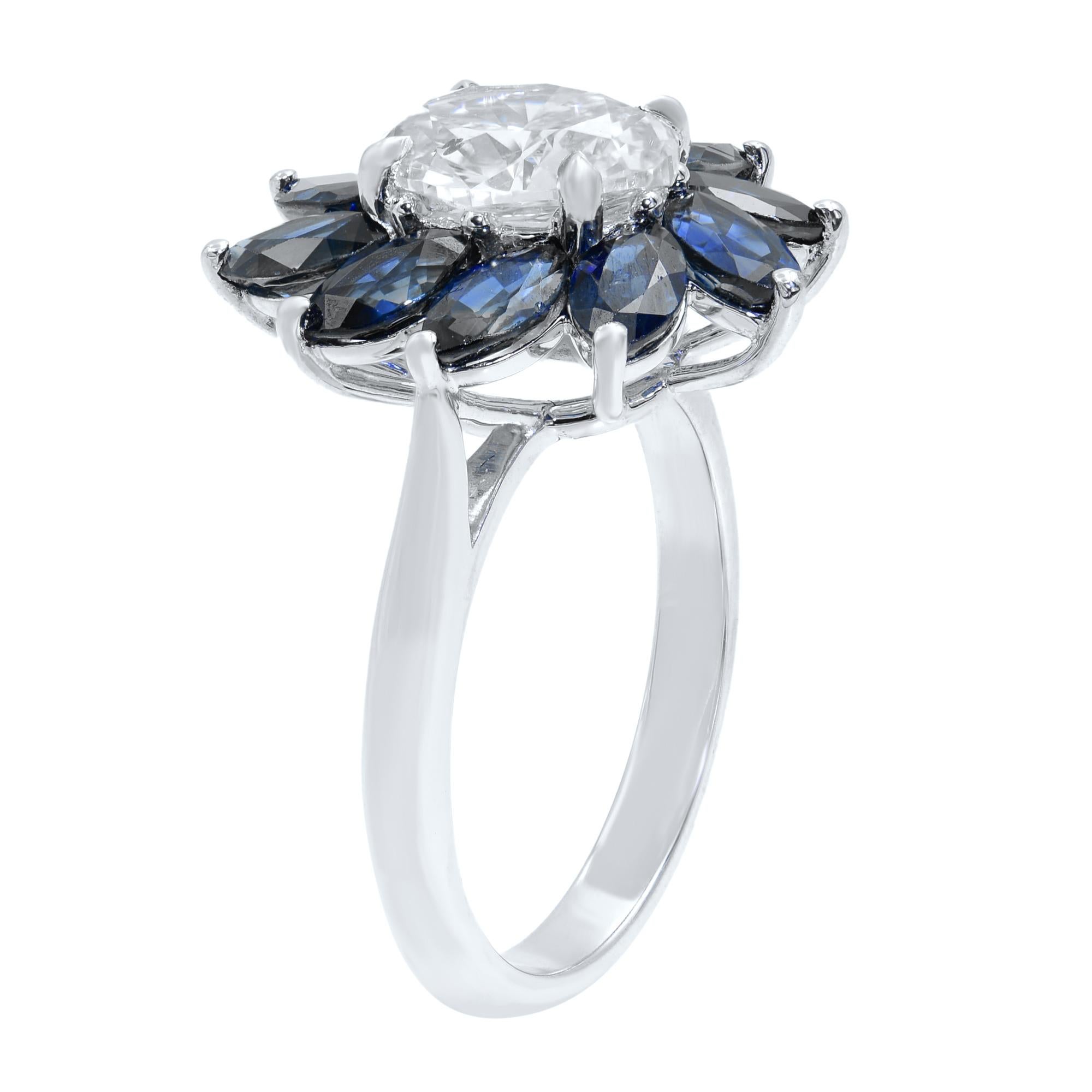 A bright white and shining oval-cut diamond, total weight, 1.51 carat, centers sparkling marquise-cut blue sapphire petals in this classic vintage-style flower ring recently crafted in our very own jewelry shop. One of a kind oval cut diamond
