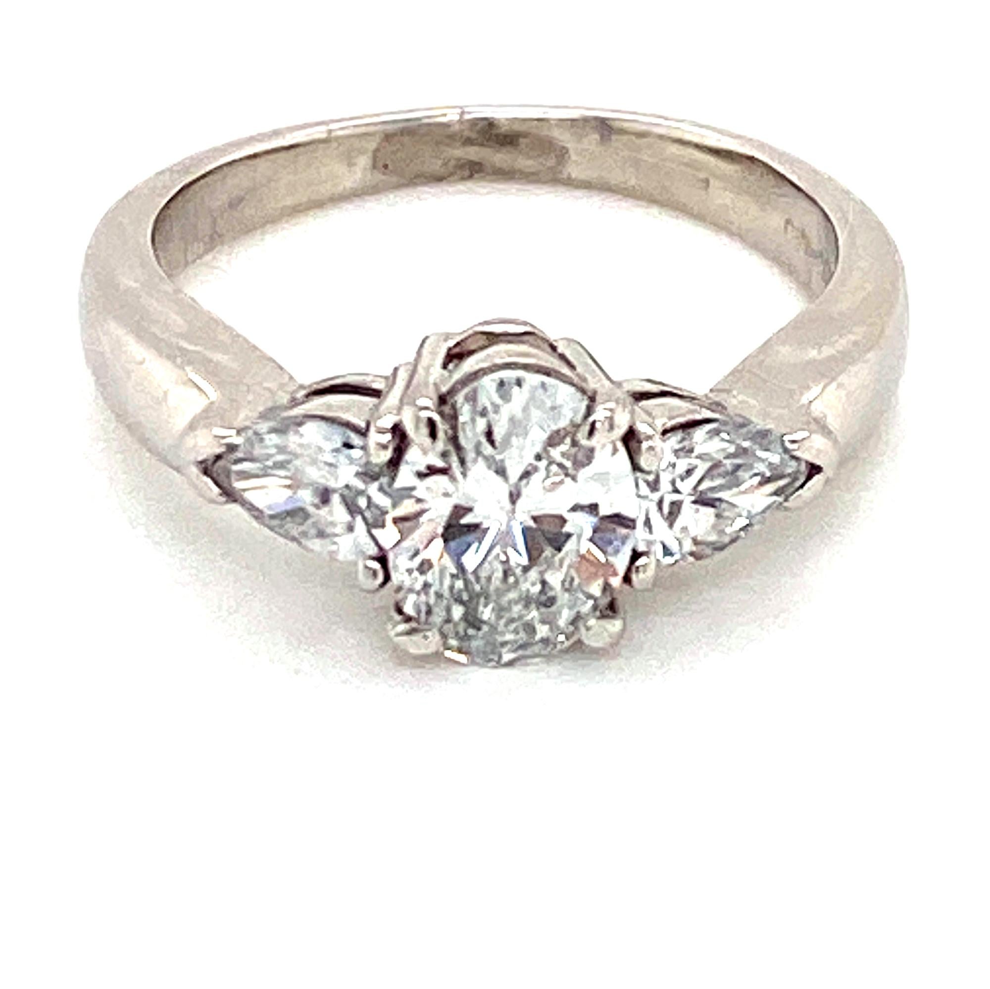 Diamond engagement ring fashioned in platinum. The oval cut diamond weighs .76 carats and is GIA certified F color and VS1 clarity. The oval is flanked by two pear shape diamonds weighing .40 carat total weight. The ring is currently size 5.5 (can