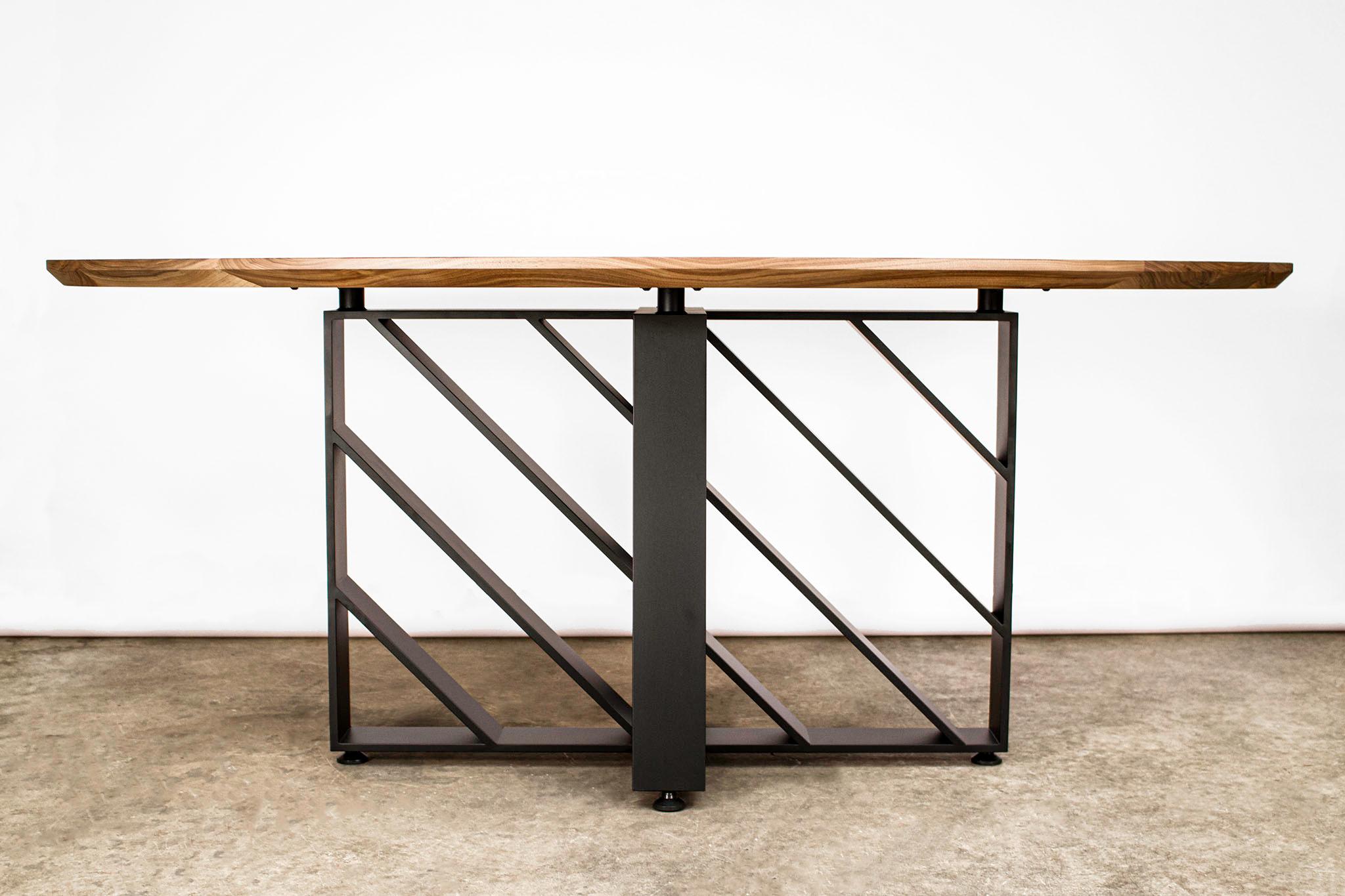 This modern blackened steel and hardwood oval table looks different from every angle because of the steel planes movement of light and shadow. Made from American Black Walnut and 1/2” x 5” hot rolled steel plate with a live blackened finish.