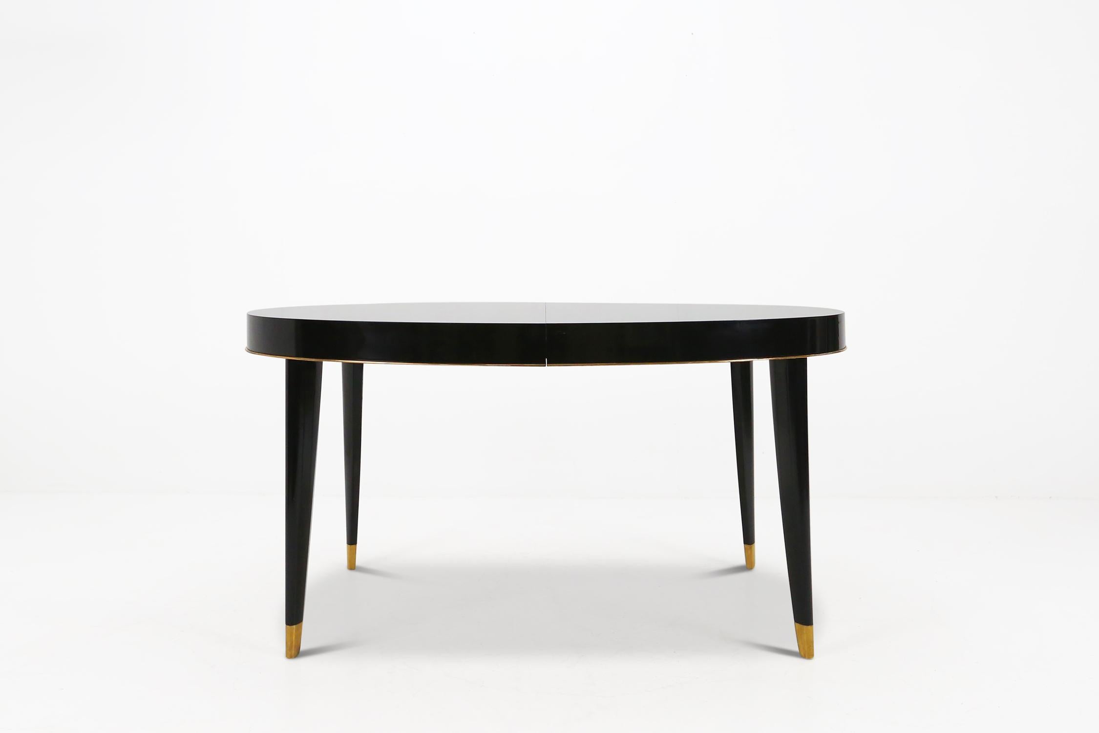 Art Deco dining table by De Coene Belgium made around 1940.
Made of black piano lacquered wood and polished brass feet.
The extensions for the table are no longer present.