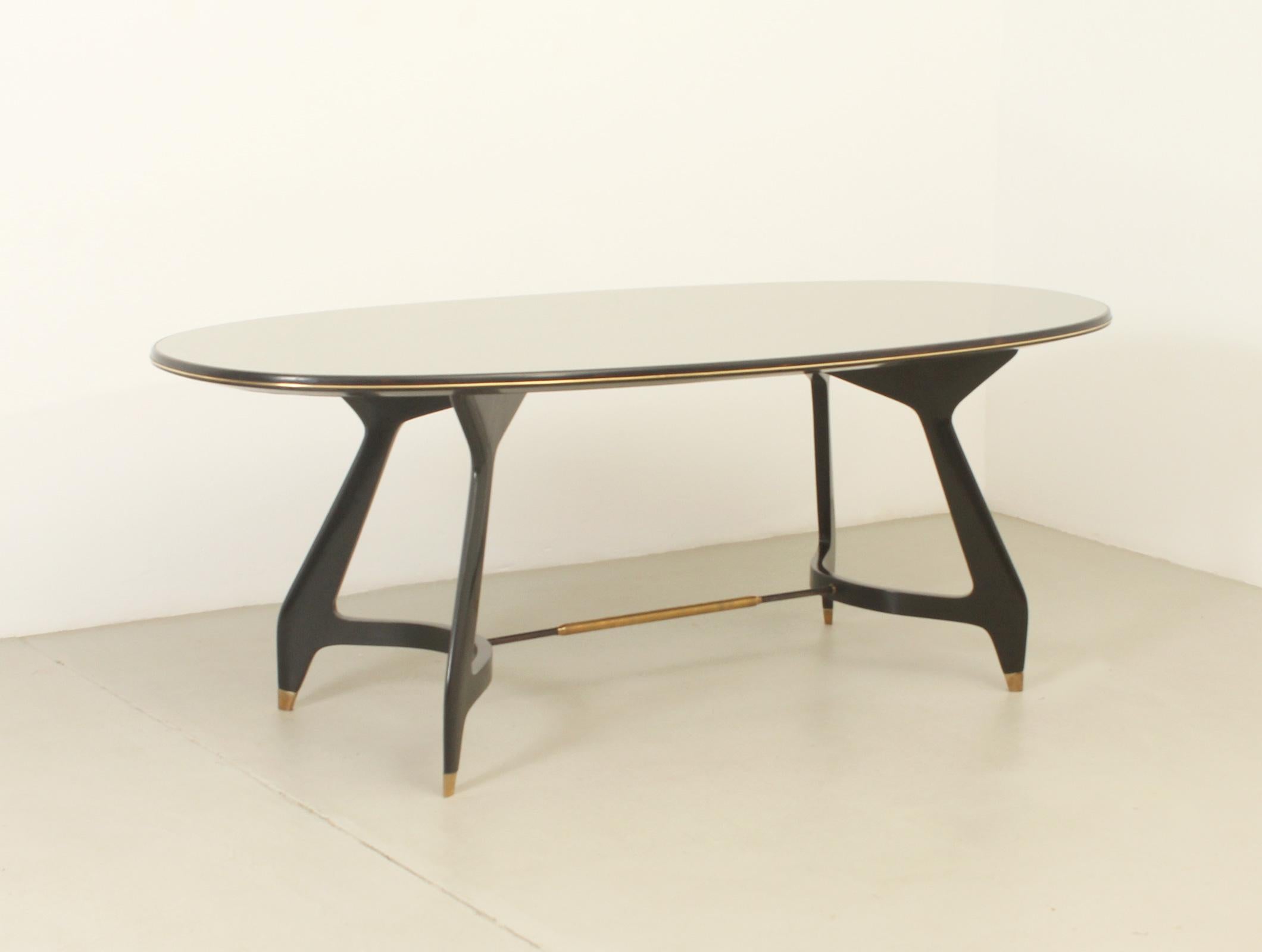 Oval dining table designed by Vittorio Dassi in 1950's, Italy. Ebonized maple wood structure with brass fittings and original curved green glass top with gold decoration. 