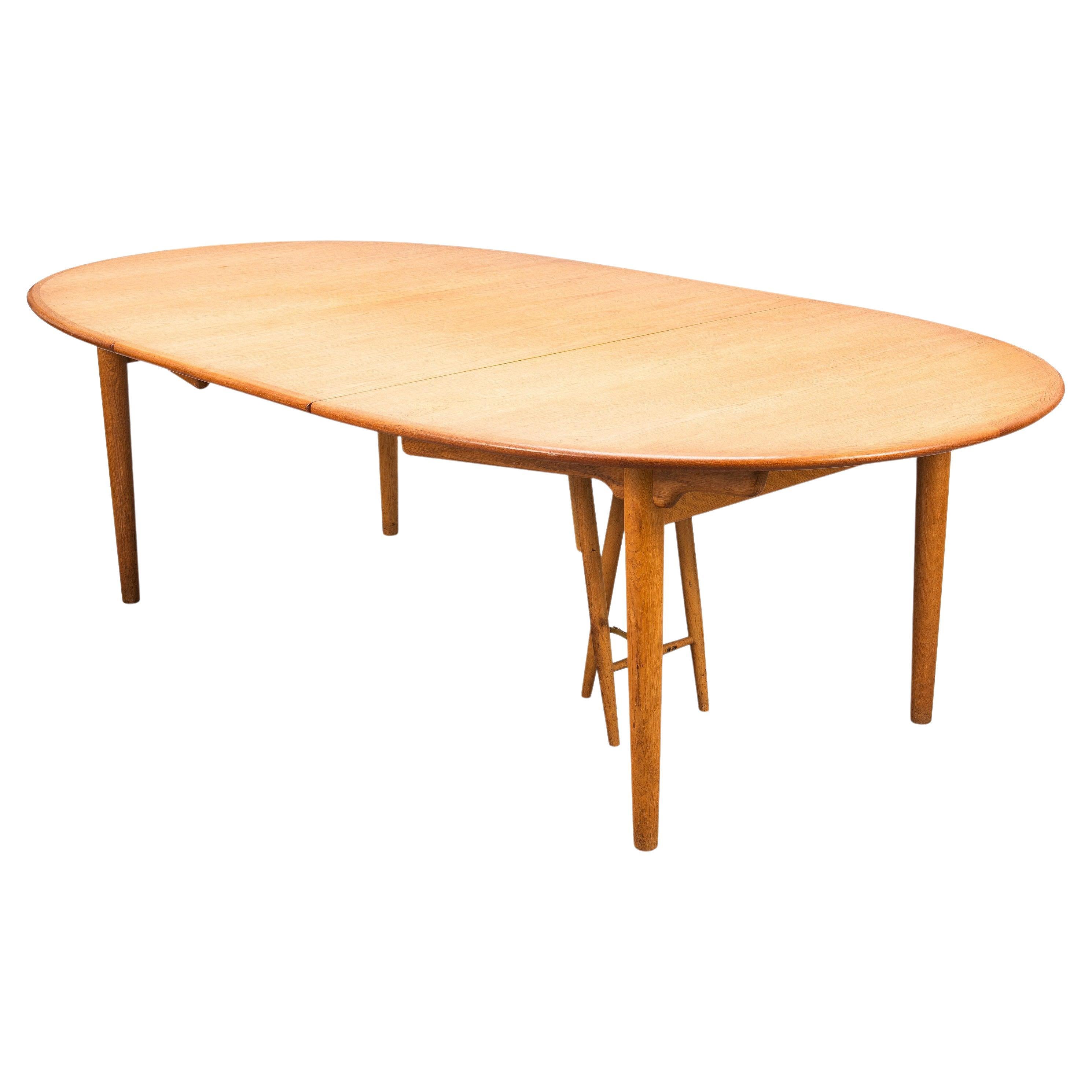 Hans J. Wegner oval table model JH567 for Johannes Andersen, extendable dining table solid oak, Denmark, 1950's. The oval tabletop has one additional leaf in order to expand the table from 178cm to 241.5 cm. Restored to eliminate glass rings and