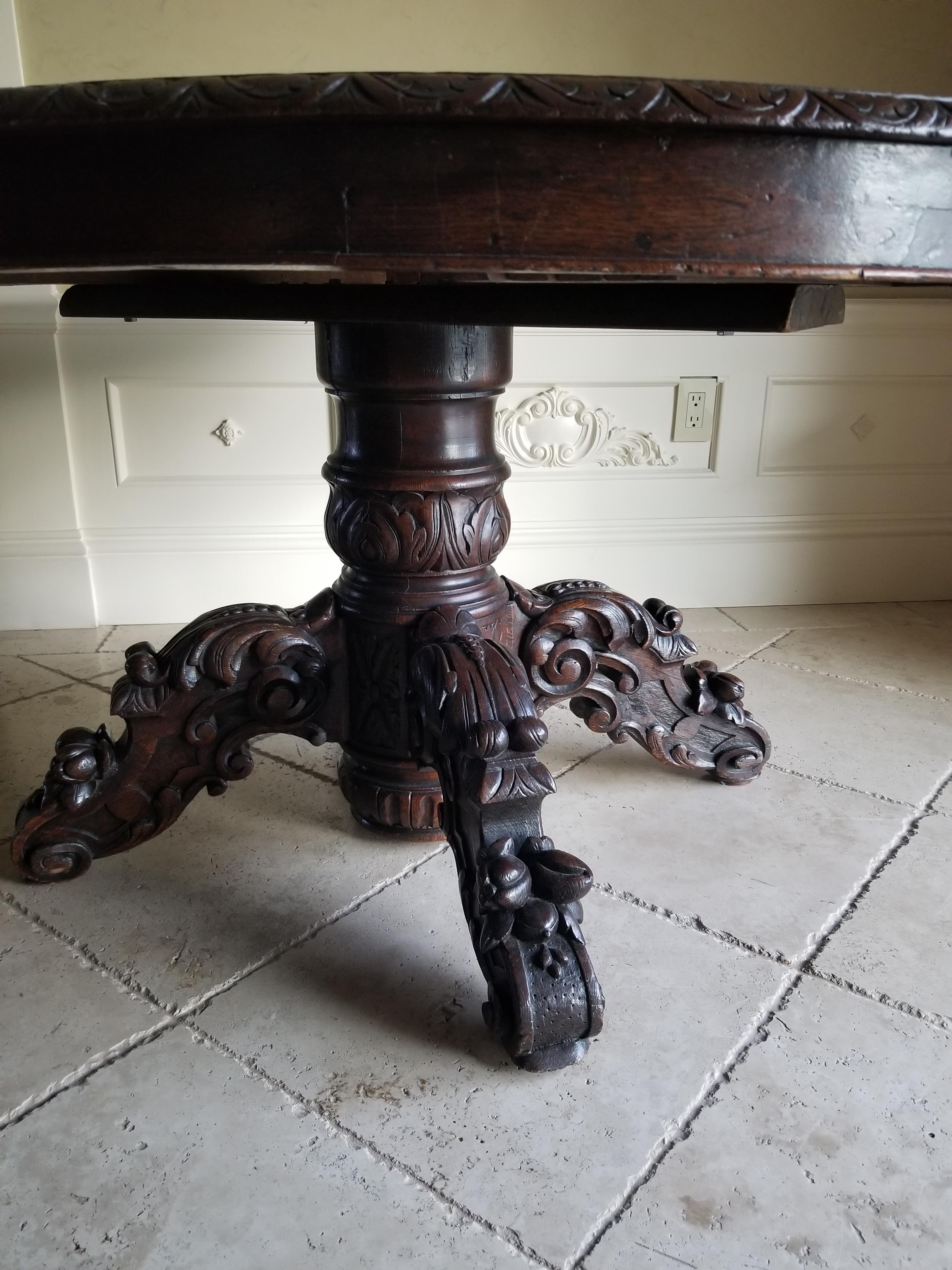 Well-proportioned early 19th century walnut wood table on a carved pedestal base. Hand planed, hand carved solid wood table with one extension insert. Without the extension it is almost round and with the extension it is oval. The picture shows how
