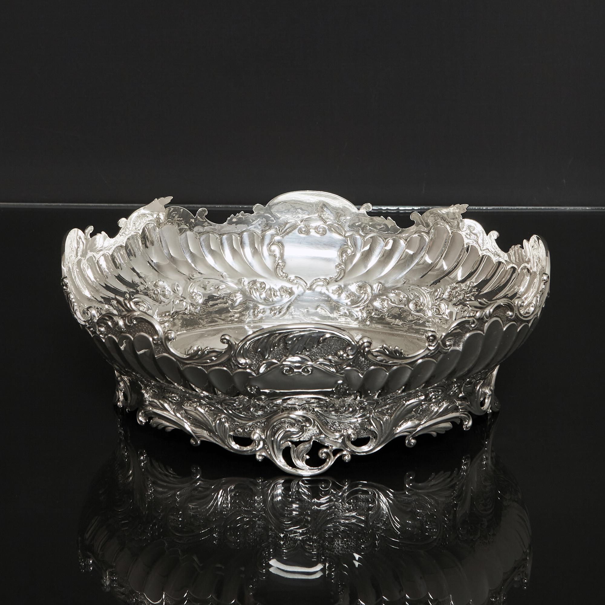 A shallow oval antique silver bowl with scalloped rim and cast openwork foot. This attractive silver piece will make a wonderful centrepiece for a dining table and could be used for a fruit or flower display. The shaped border is cast with leaf and
