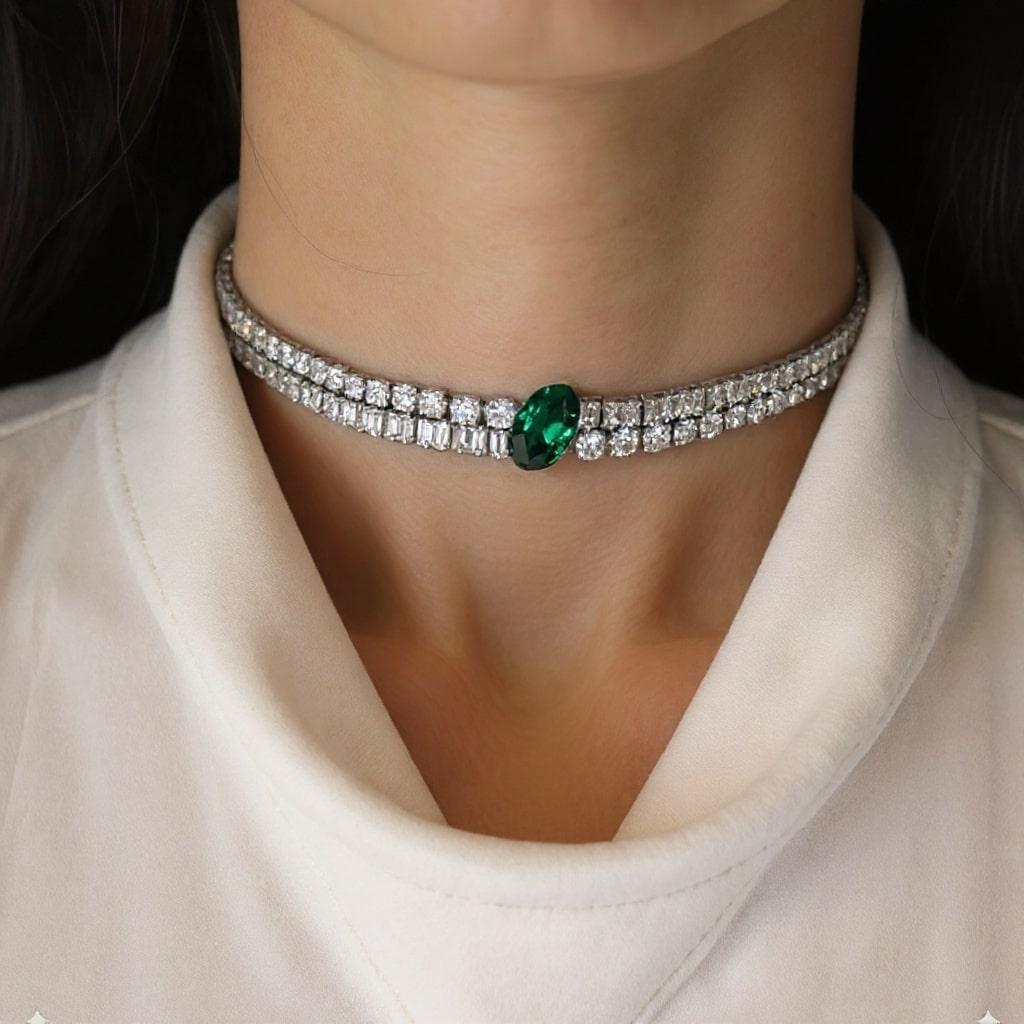 Dieses exquisite Collier aus strahlendem 18-karätigem Weißgold zeichnet sich durch eine durchgehende Linie von Brillanten im klassischen Tennis-Design aus. In der Mitte ruht ein lebendiger Smaragd im Ovalschliff, dessen satter grüner Farbton einen
