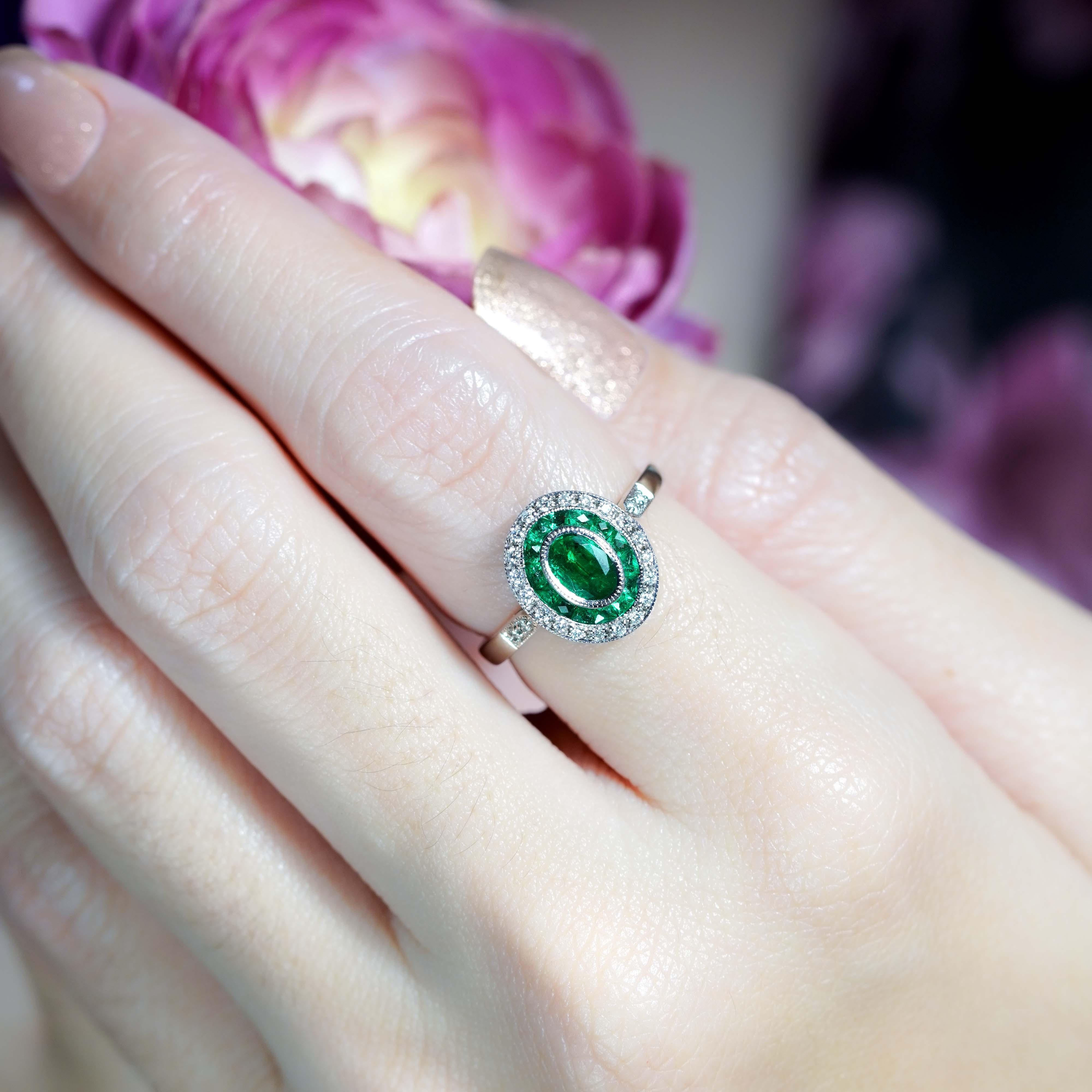 Fai una dichiarazione d'effetto con questo anello di fidanzamento target con smeraldo ovale e diamanti in stile Art Deco. Uno smeraldo ovale da 0,5 carati incastonato è al centro della scena, circondato da una vibrante aureola di smeraldi taglio