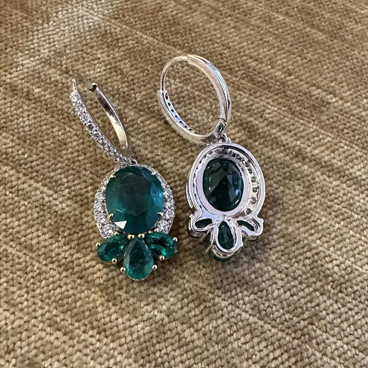 Oval Emerald and Diamond Drop Earrings in 18k White Gold

Emerald and Diamond Earrings features 2 large Oval Green Emeralds surrounded by Round Diamonds with Oval and Pear Emeralds at the bottom, all set in 18k White Gold. The earrings are secured