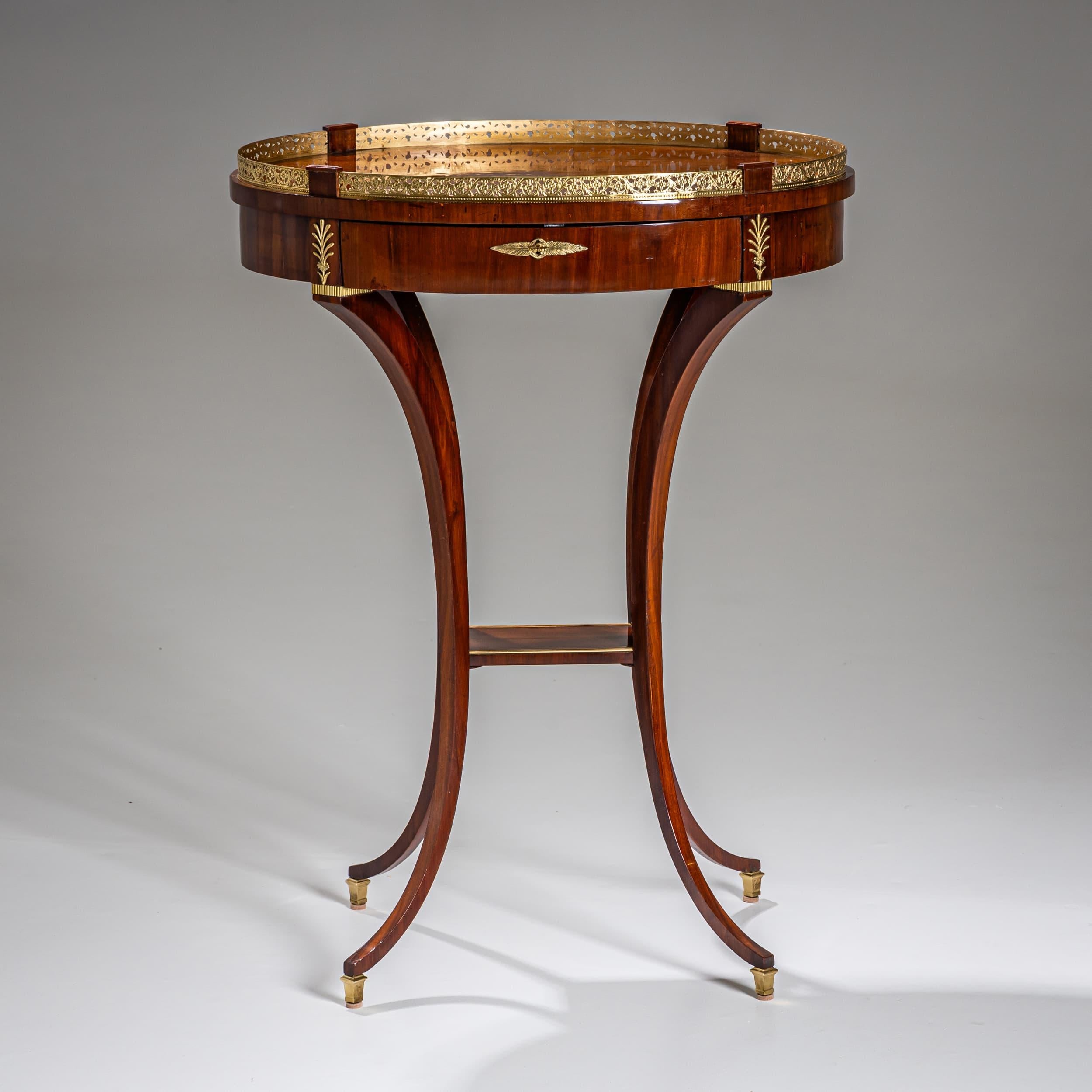 Délicate table d'appoint Empire du début du XIXe siècle, plaquée d'acajou et dotée d'un seul tiroir. Les pieds gracieusement incurvés en forme de C se terminent par des sabots en laiton et sont reliés par un châssis rectangulaire garni de profils en