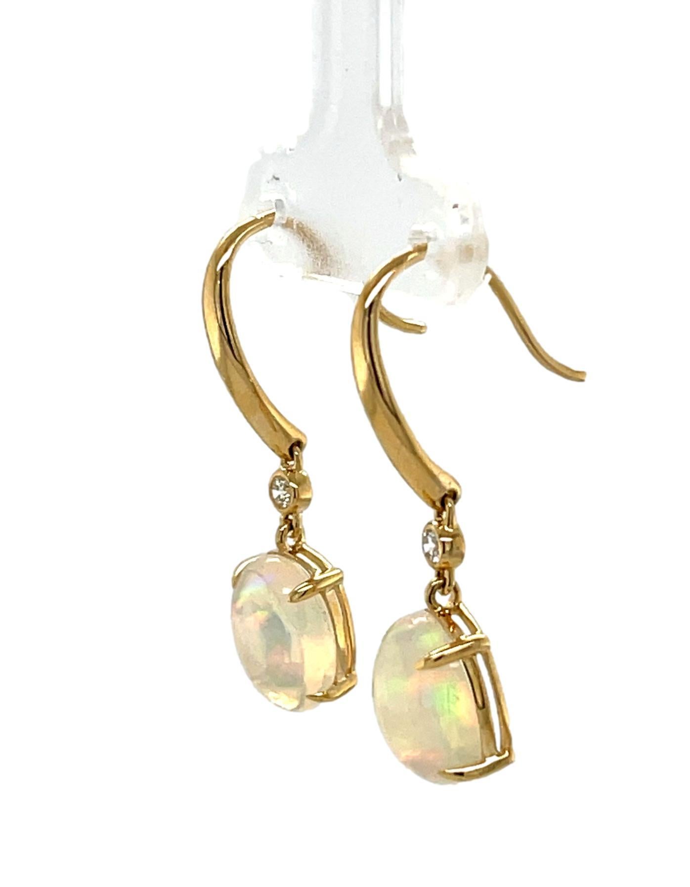 These stunning Ethiopian Opal and diamond dangling Hoop earrings are 4 prong set in 14 karat yellow gold. There is one sparkling brilliant cut round diamond on top of the stone for a beautiful accent. These earrings are approximately 1.25 inches in