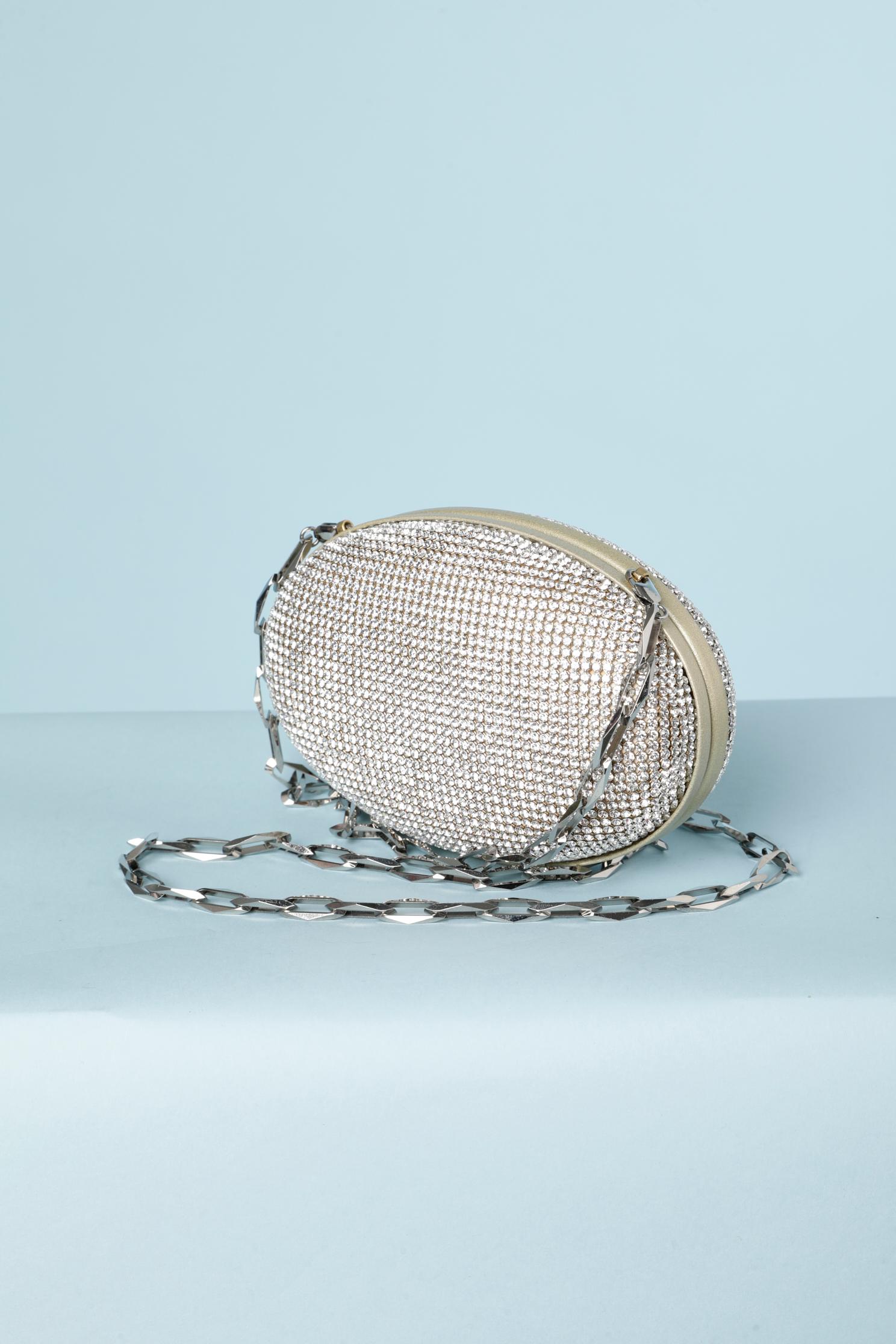 Oval Evening bag in rhinestone and pale gold leather. Strap in smoked metallic silver. 
Size: 15 cm X 10 cm X 4 cm 
Lining and edge in pale gold leather. 
Detachable strap. 