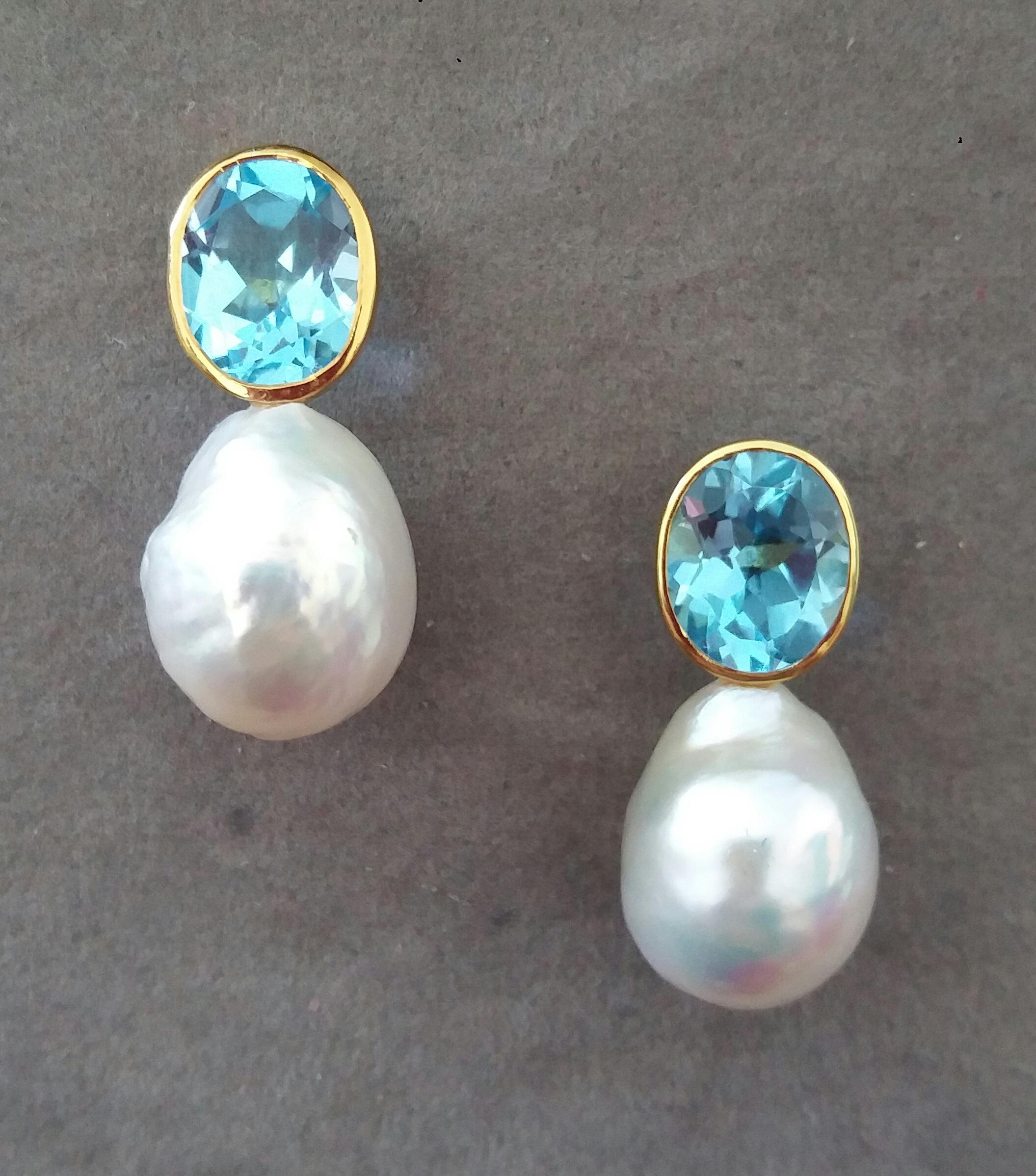 Estos pendientes, sencillos pero elegantes y totalmente hechos a mano, tienen 2 Topacios Azules Ovalados Facetados que miden 8x 10 mm engastados en un bisel de oro amarillo de 14 Kt en la parte superior del que cuelgan 2 Perlas Barrocas Blancas en