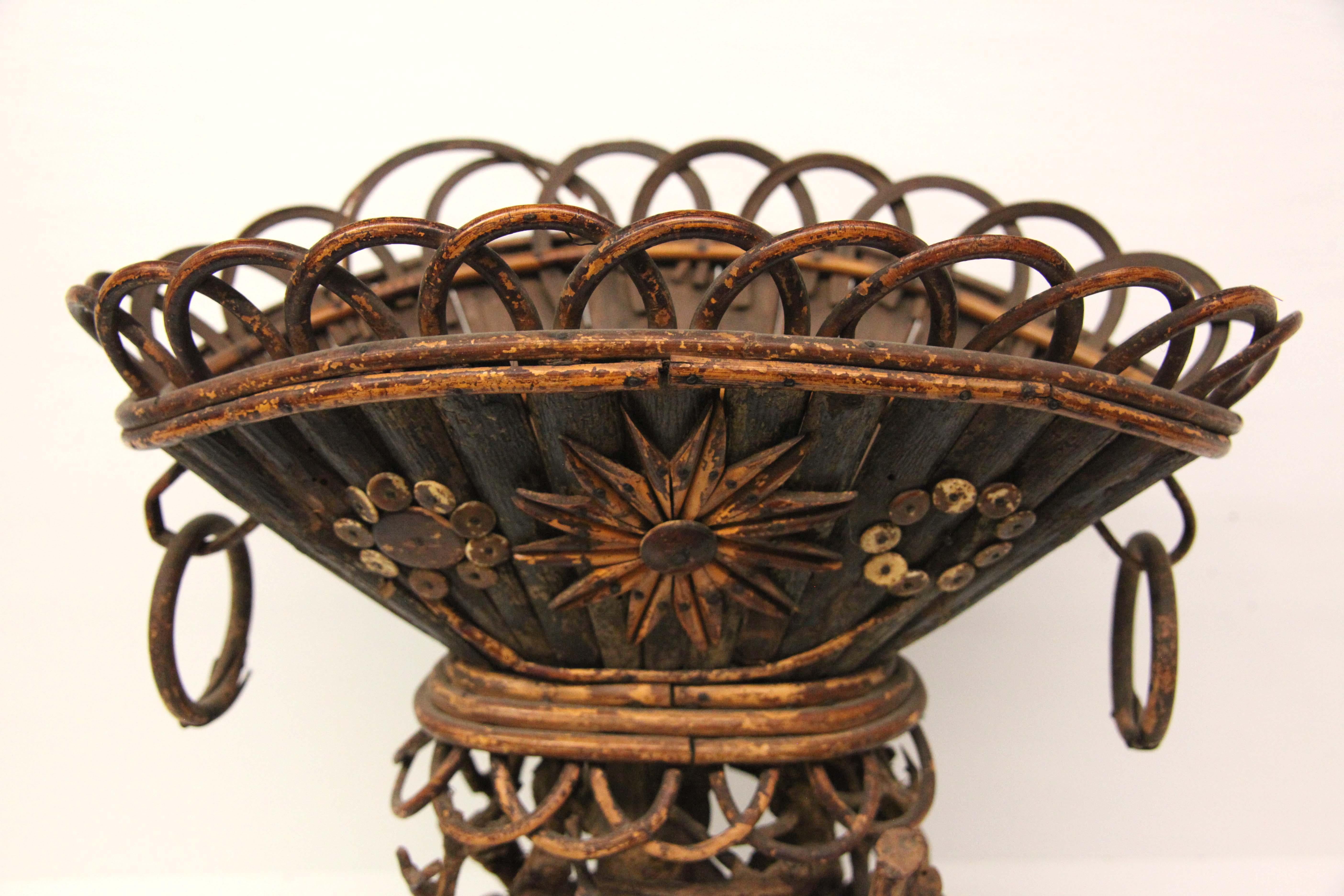 Oval Folk Art basket centerpiece, the rim consisting of bent bamboo semi circles attached to the oval basket of individual slices of wood held together inside with a ring of bamboo, this resting on '' stumps '' of wood of various shapes and sizes,