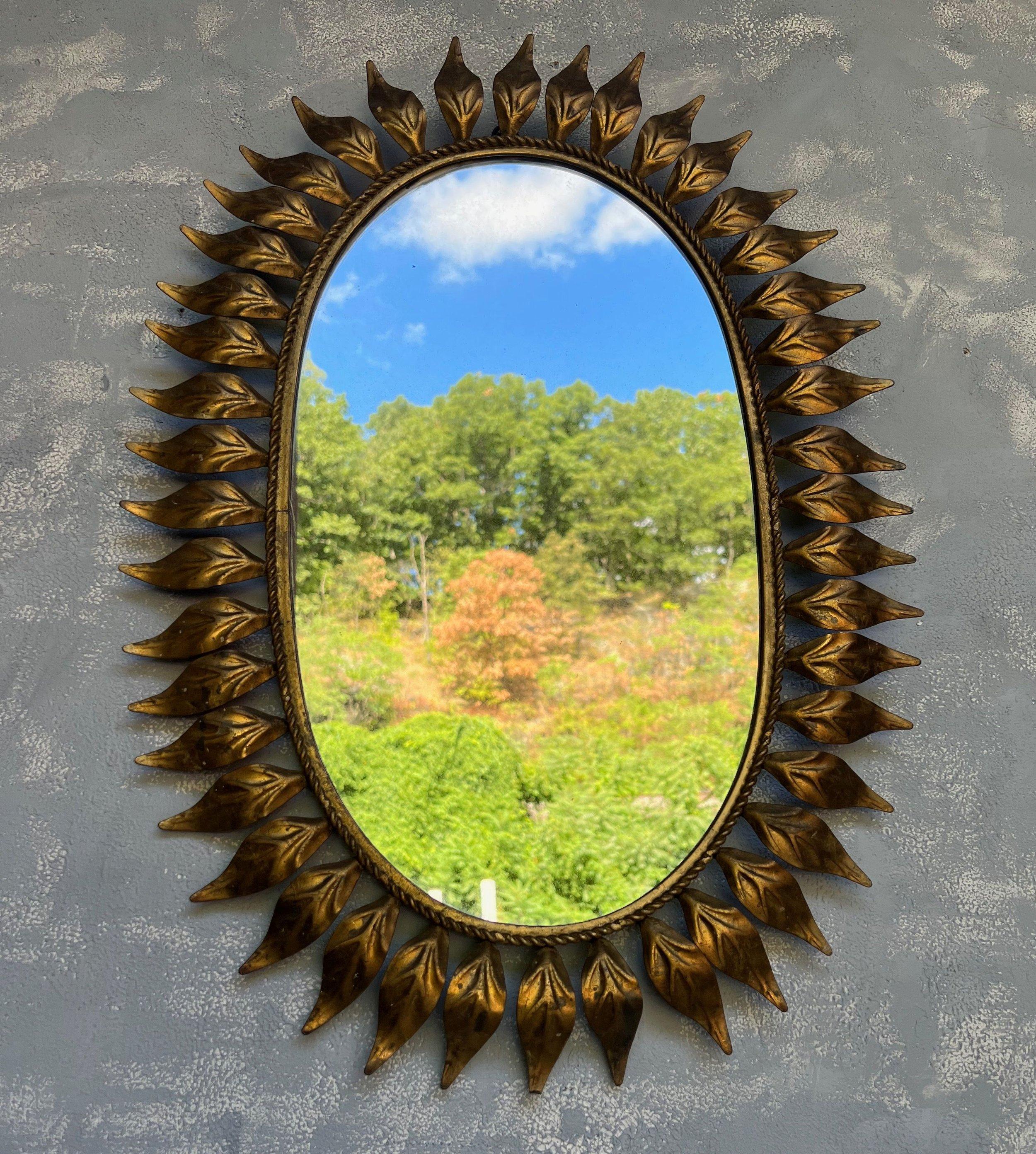This lovely mid century oval gilt metal sunburst mirror features small pointed rays surrounding a braided interior frame. The metal has a richly gilt patina, original to the piece. We have added a felt backing to give the mirror more protection as