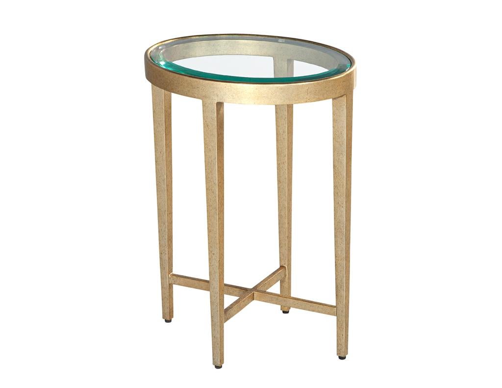 Elevate your entertaining space with this stunning contemporary drinks table. Its sleek, oval design features a beveled-edge glass top, perfectly balanced on a slender metal frame finished in a lustrous faux gold leaf. This elegant piece is the