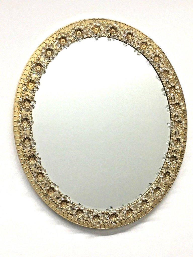 Stunning midcentury oval glass mirror by German manufacturer Palwa. The gold-plated brass frame is decorated with delicate flowers made from faceted crystals and beads. The centre of the flower is finished with a gold-plated detail bolting the