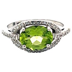 Anillo ovalado de peridoto verde y halo de diamantes en oro blanco de 14k