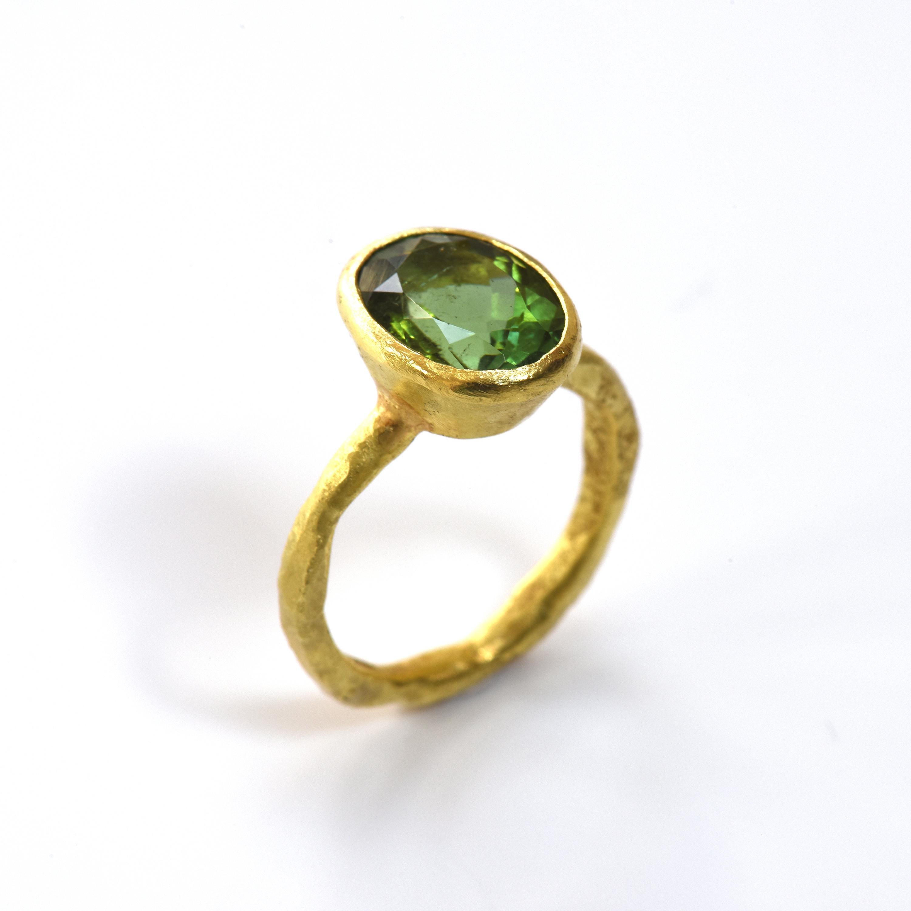 Oval bottle green tourmaline approximately 5 carats, set in an 18k yellow gold tapered rub over setting on 18k yellow gold organic textured band.

Disa Allsopp is an internationally renowned goldsmith based in London, UK. She is known for her use of