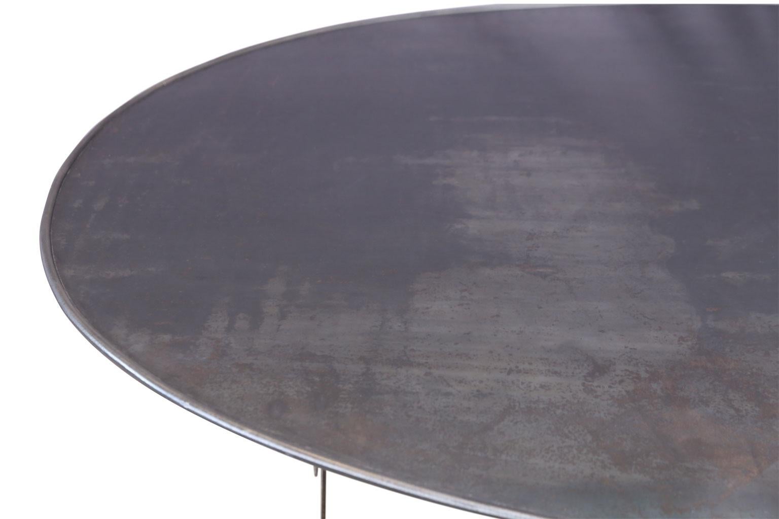 Oval hand forged steel table with rounded edge raised-rim top. This transition table is ideal for both outdoor and indoor dining. This table is a custom order with a six to eight week turn-around (not including time spent in transit shipping).