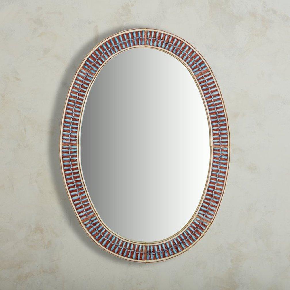 A remarkable 1960s wall mirror sourced in France. This mirror features an oval frame composed of eight curved, hand-painted ceramic tiles in vibrant blue and maroon hues. The tiles are from Vallauris, a region in France historically recognized for