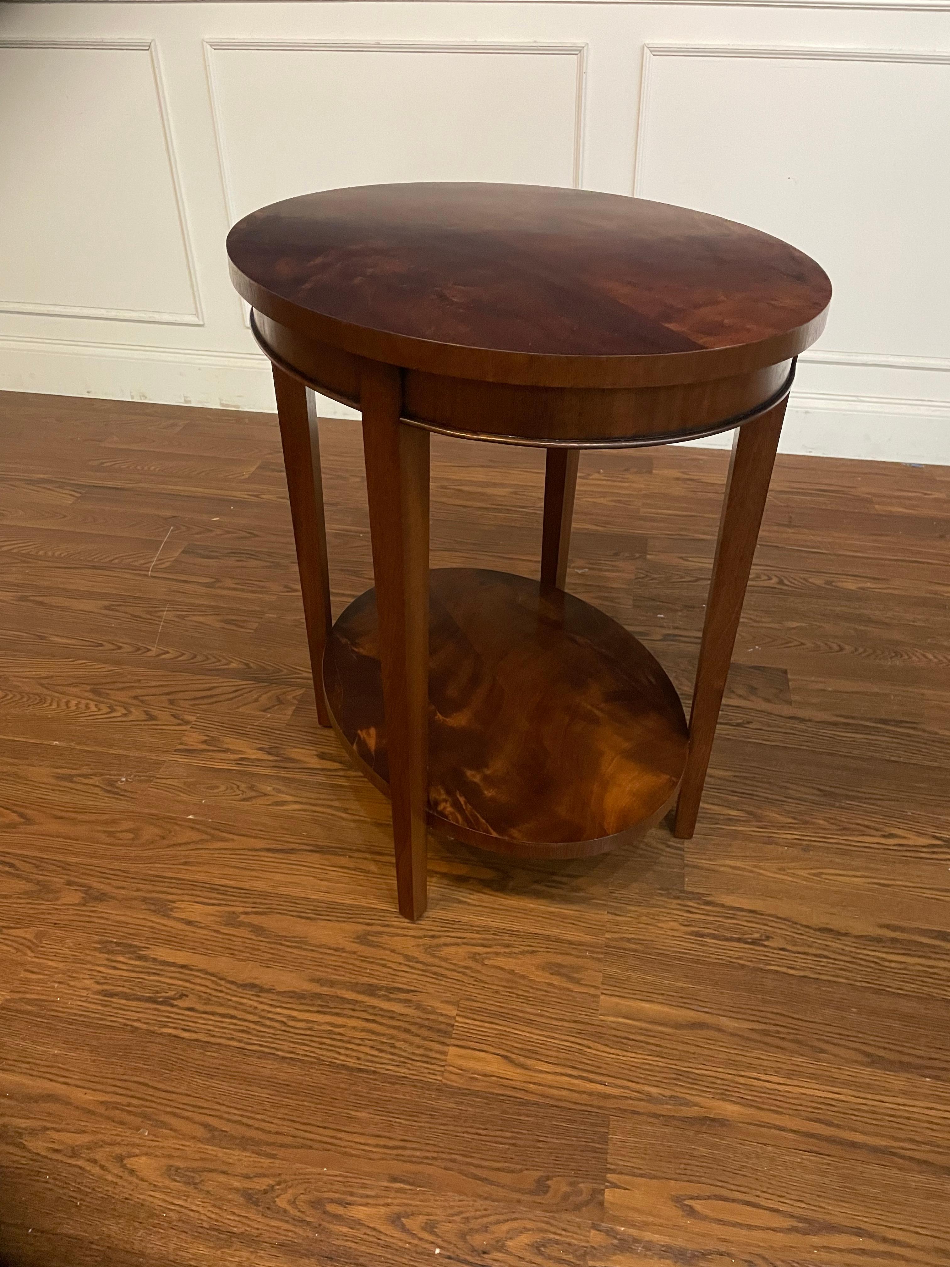 This is an oval Hepplewhite style mahogany side table made to order in our shop in Suwanee, Georgia.  It features classic Hepplewhite styling with square tapered legs.  The top and the lower shelf have a reverse slip match pattern of swirly crotch