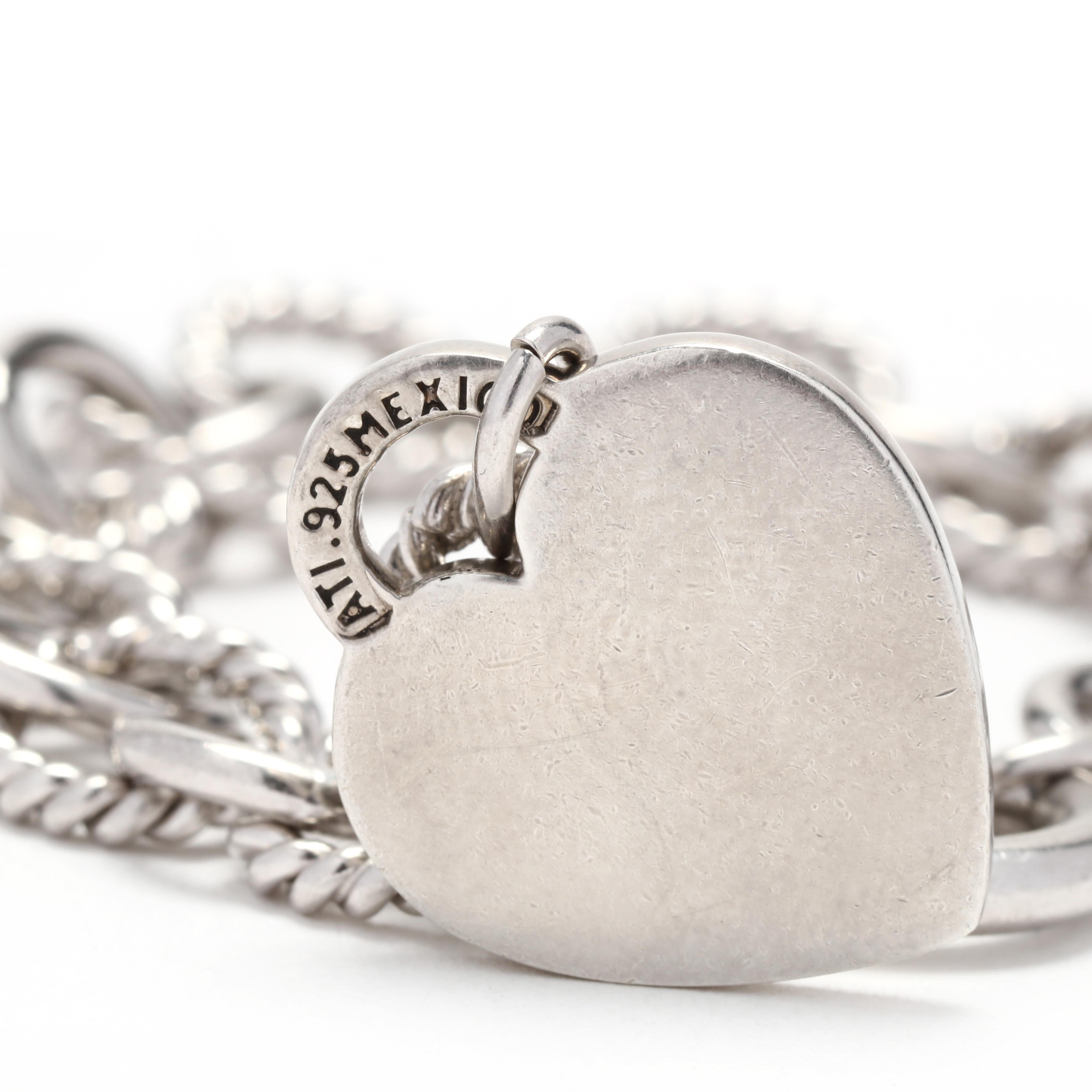 A sterling silver oval link heart charm bracelet.  This bracelet features alternating polished and rope twist oval links and a heart-shaped lock motif charm.  It is completed with a bold spring ring clasp.  The charm is stamped ATI 925