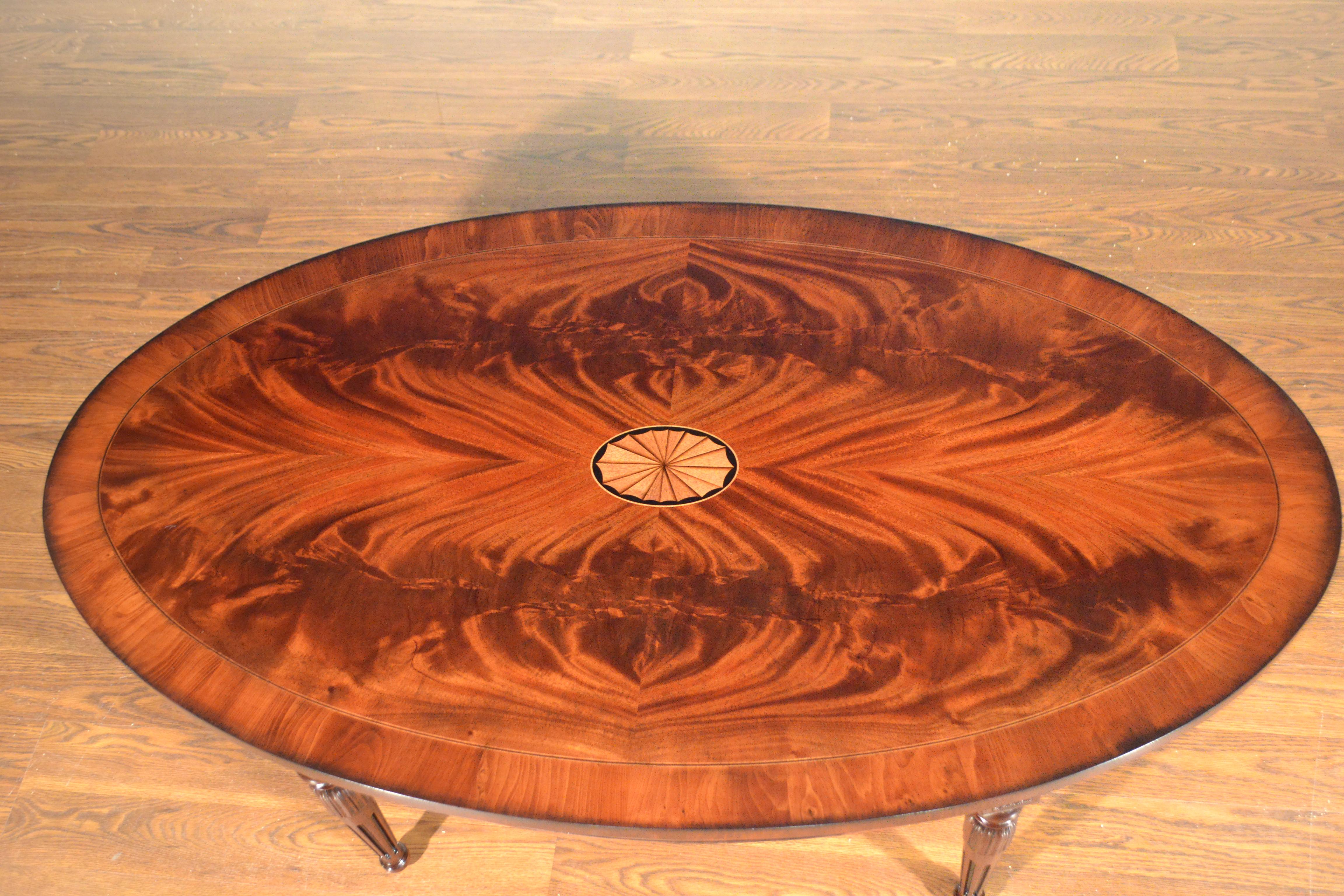 This is a made-to-order traditional oval mahogany coffee table made in the Leighton Hall shop. It features a field of booked and butted crotch mahogany and a border of Yew wood with a center medallion It has a hand rubbed and polished semigloss