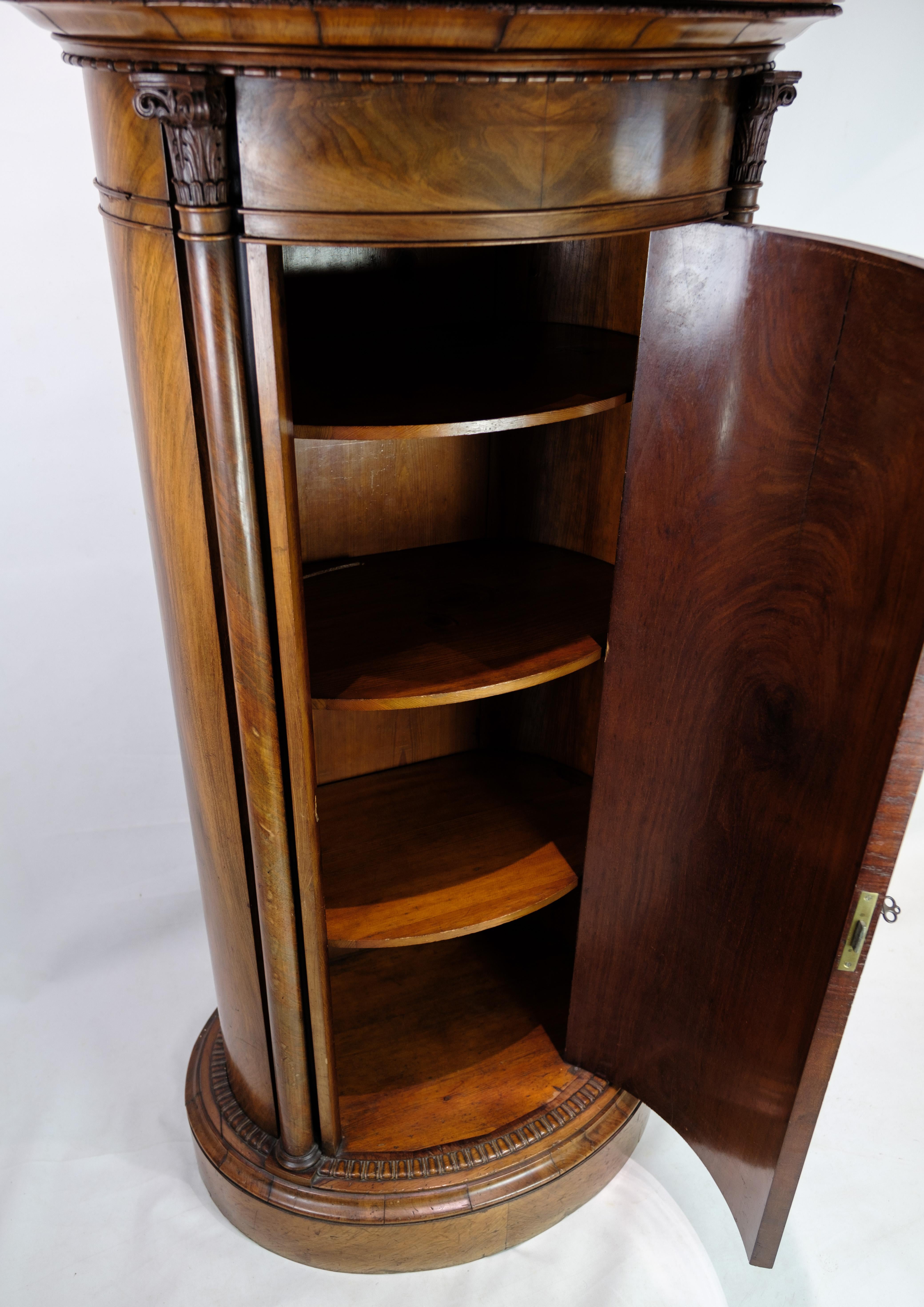 Oval pedestal cabinet decorated with mahogany carvings from around the 1820s.
Measurements in cm: H:143 W:71 D:44
