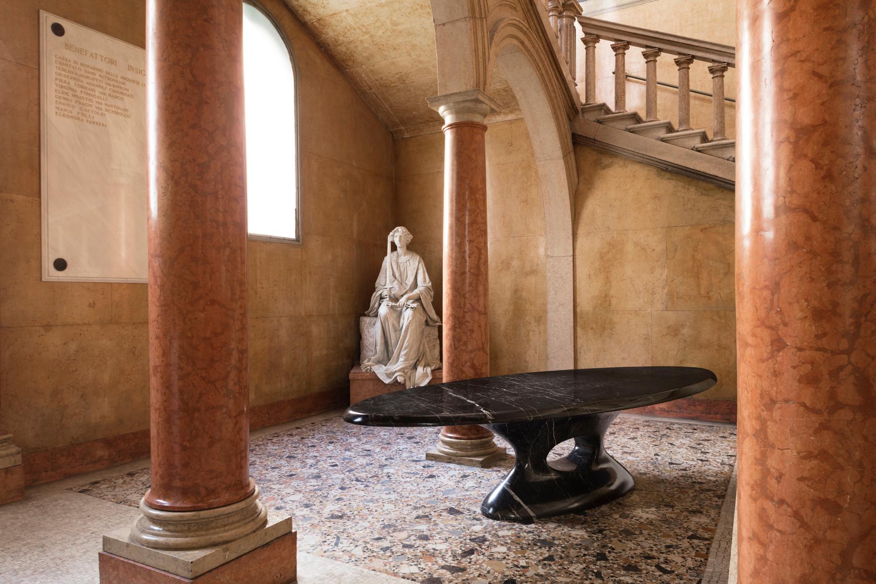 Il tavolo ha una forma che ricorda le figure dei dipinti del Rinascimento.
Il tavolo è scolpito da un blocco solido di marmo Nero Marquina.
Design di Mattia Biagi e Cardenio Petrucci.
Presentato al Fuori Salone della Settimana del Design di Milano