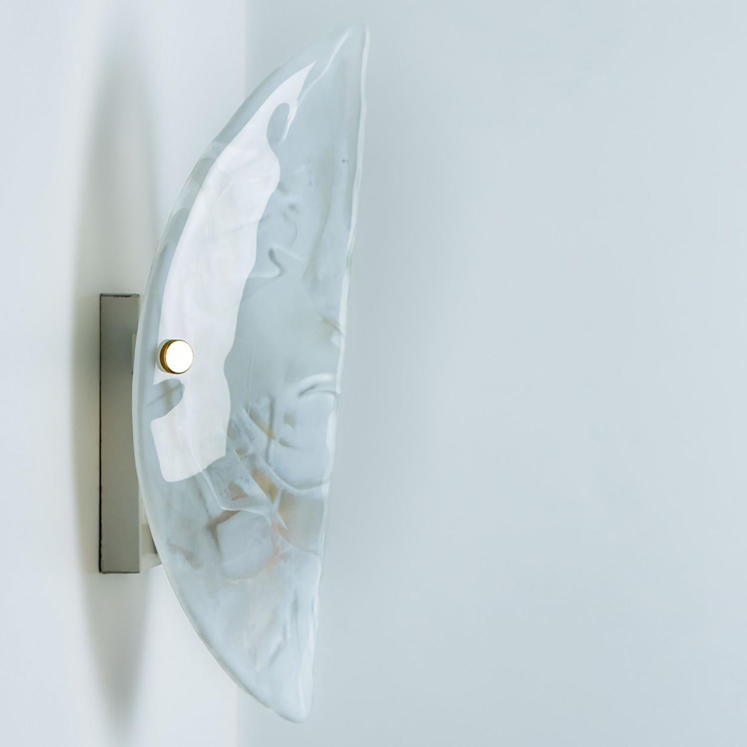Clean lines to complement all decors.  A wonderful high-end wall light fixture with silver detail and thick marbled blown glass. Manufactured in the 1960s.
The glass of the light fixtures are made of clear textured glass giving the piece a playful