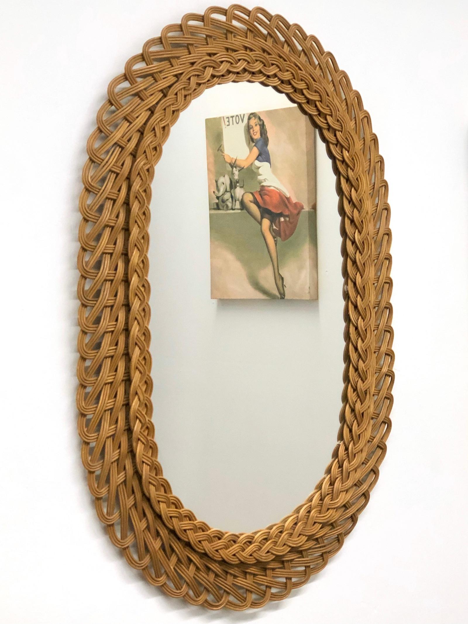 A beautiful handwoven oval shaped rattan and wicker mirror. This mirror has a handcrafted braided work at the frame that makes it highly decorative, Germany, 1960s. May be hung horizontally or vertically.