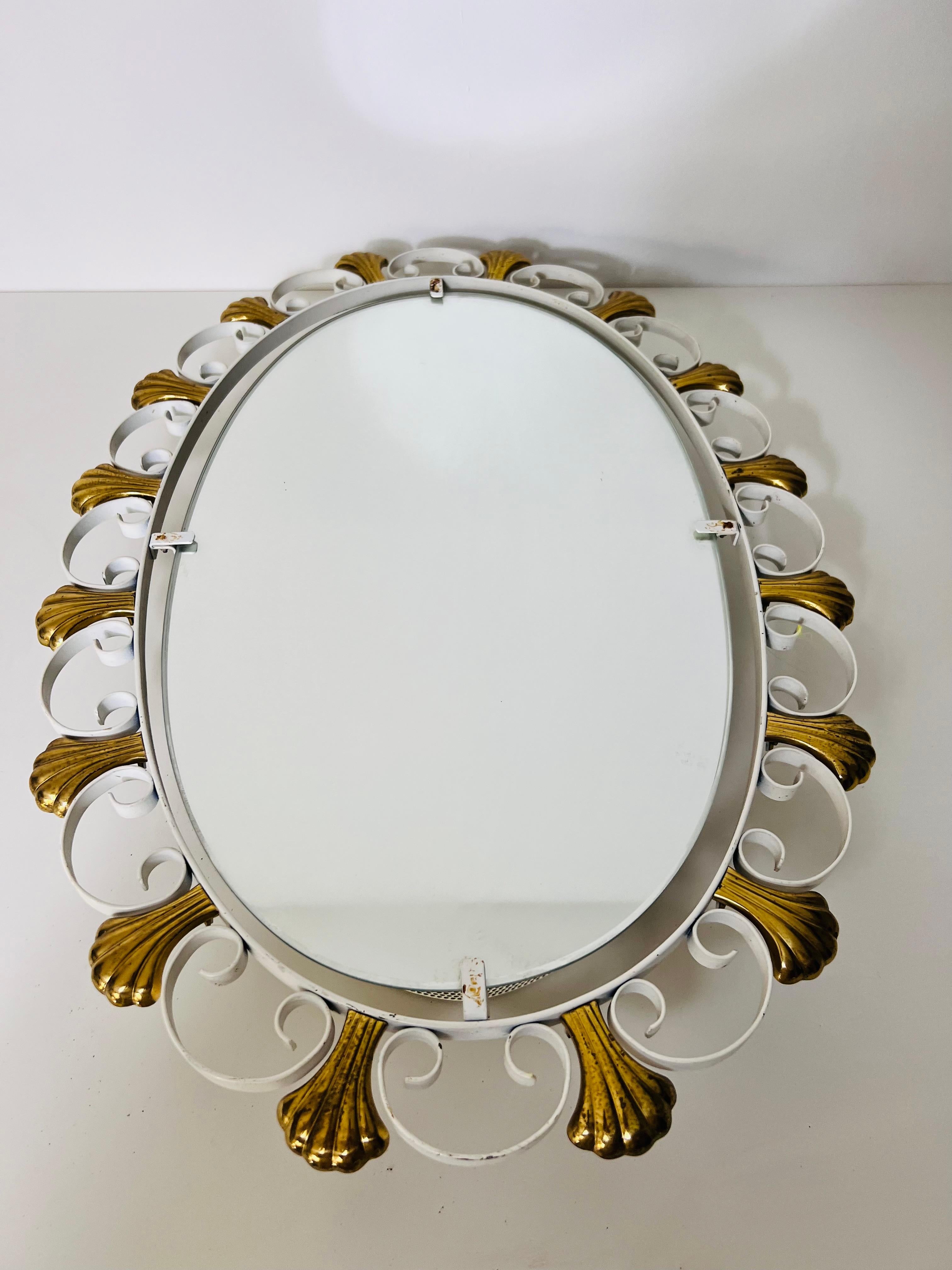 This elegant oval wall mirror, designed by Hillebrand in Germany during the 1960s, features a perforated brass metal frame that exudes mid-century modern charm. The brass elements and sleek metal construction highlight the timeless design, while the