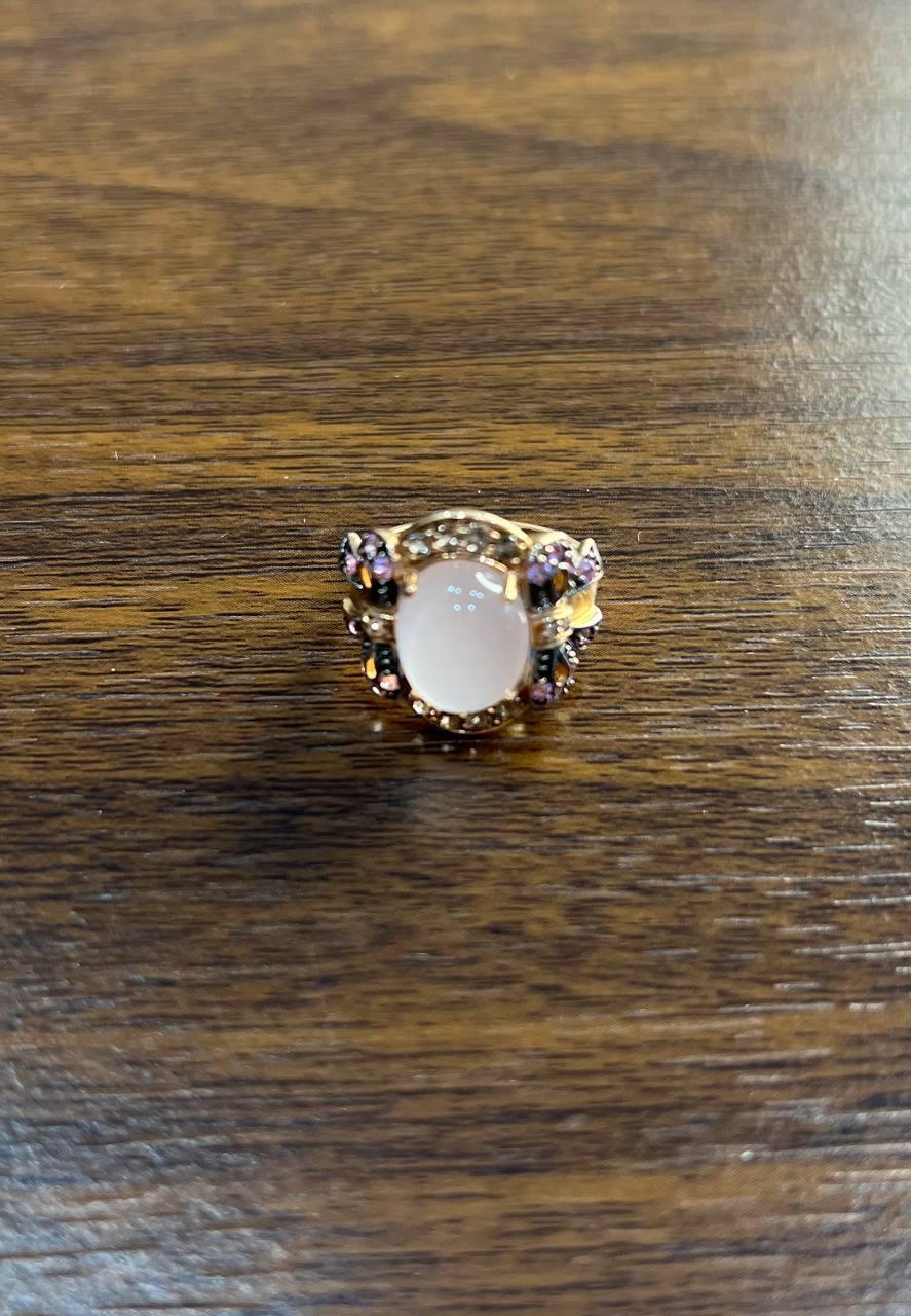 At its heart lies a mesmerizing white chalcedony, expertly cut in a cabochon style, radiating a soft, ethereal glow. The stone is elegantly framed by intricate gold detailing, enhancing its natural beauty.

The ring's design features delicate