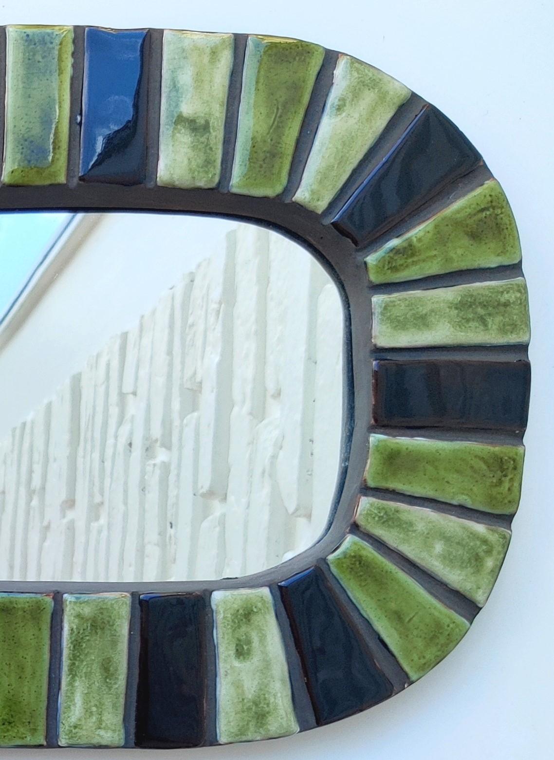 Un miroir réalisé au début de sa carrière, en terre cuite estampée et émaillée et de forme originale. Les variations infinies de teintes vertes et olivâtres, et l'émail aux mille reflets, évoquent les couleurs chaudes et ensoleillées du sud de la