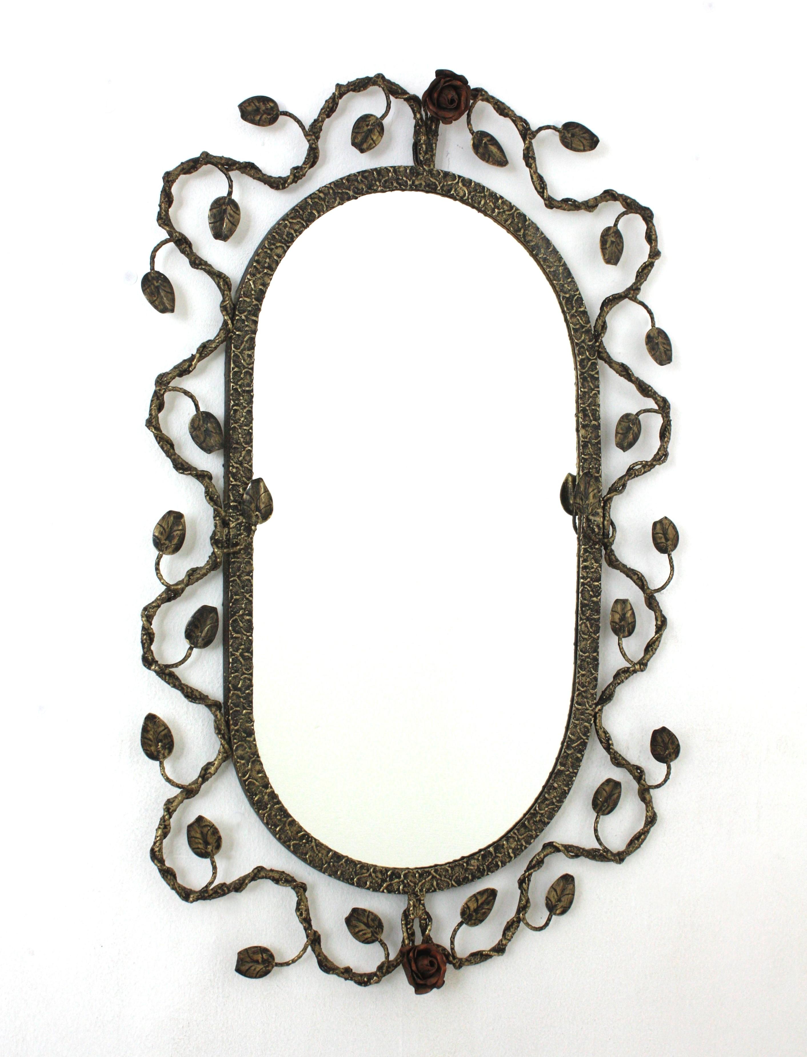 Foliage Floral Oval Mirror in Gilt Silvered Hand Forged Iron, Spain, 1950s.
Hand wrought iron oval sunburst wall mirror with foliage frame , patinated gilt-silver finish and floral accents in red patinated iron. 
The frame features and intrincate of