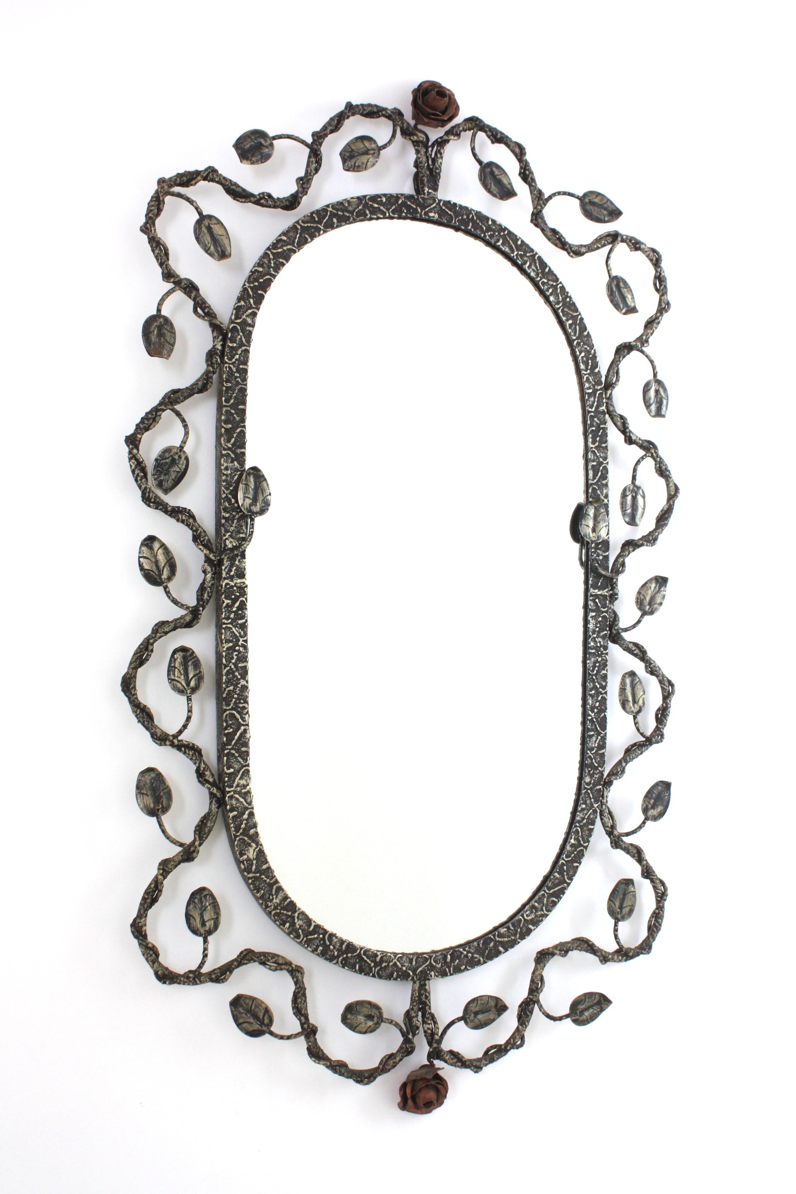 Foliage Floral Oval Mirror in Silver Silver Patinated Hand Forged Iron, Spain, 1950s.
Hand wrought iron oval sunburst wall mirror with foliage frame , silver leaf and patinated finish and floral accents.
The frame features and intrincate of branches