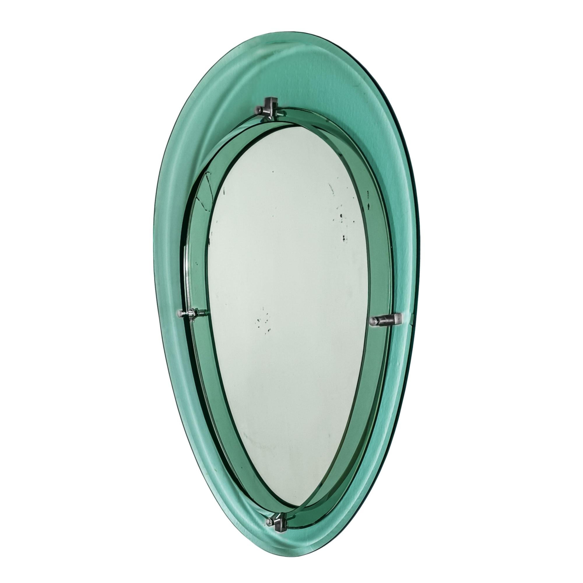 Miroir ovale avec un cadre en verre biseauté turquoise. Système d'attache en métal nickelé entre les deux parties. Traces d'oxydation.

Italie circa 1950