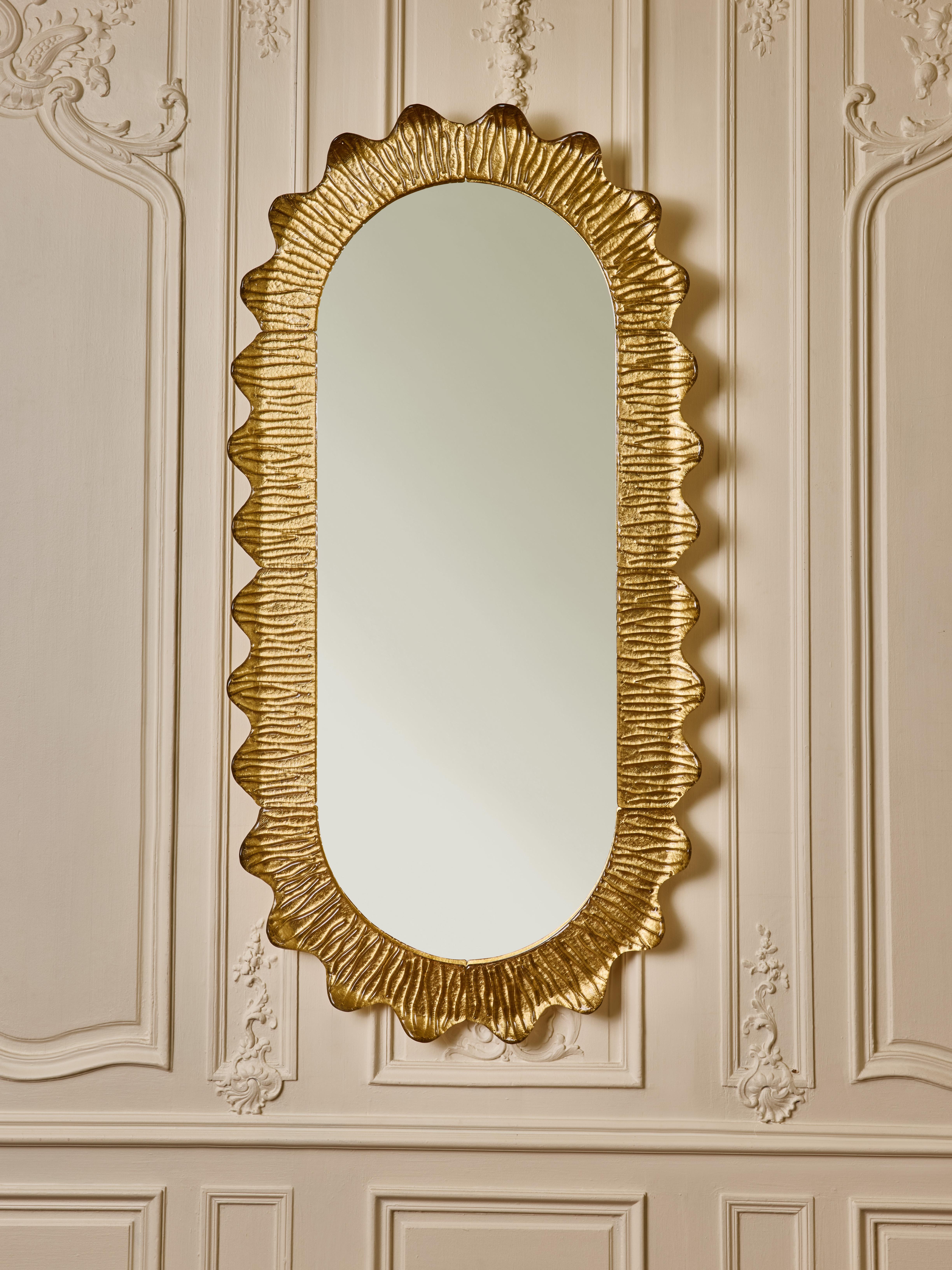 Splendido specchio da parete ovale con cornice in vetro di Murano scolpito e dorato.
Creazione dello Studio Glustin.
Italia, 2025

