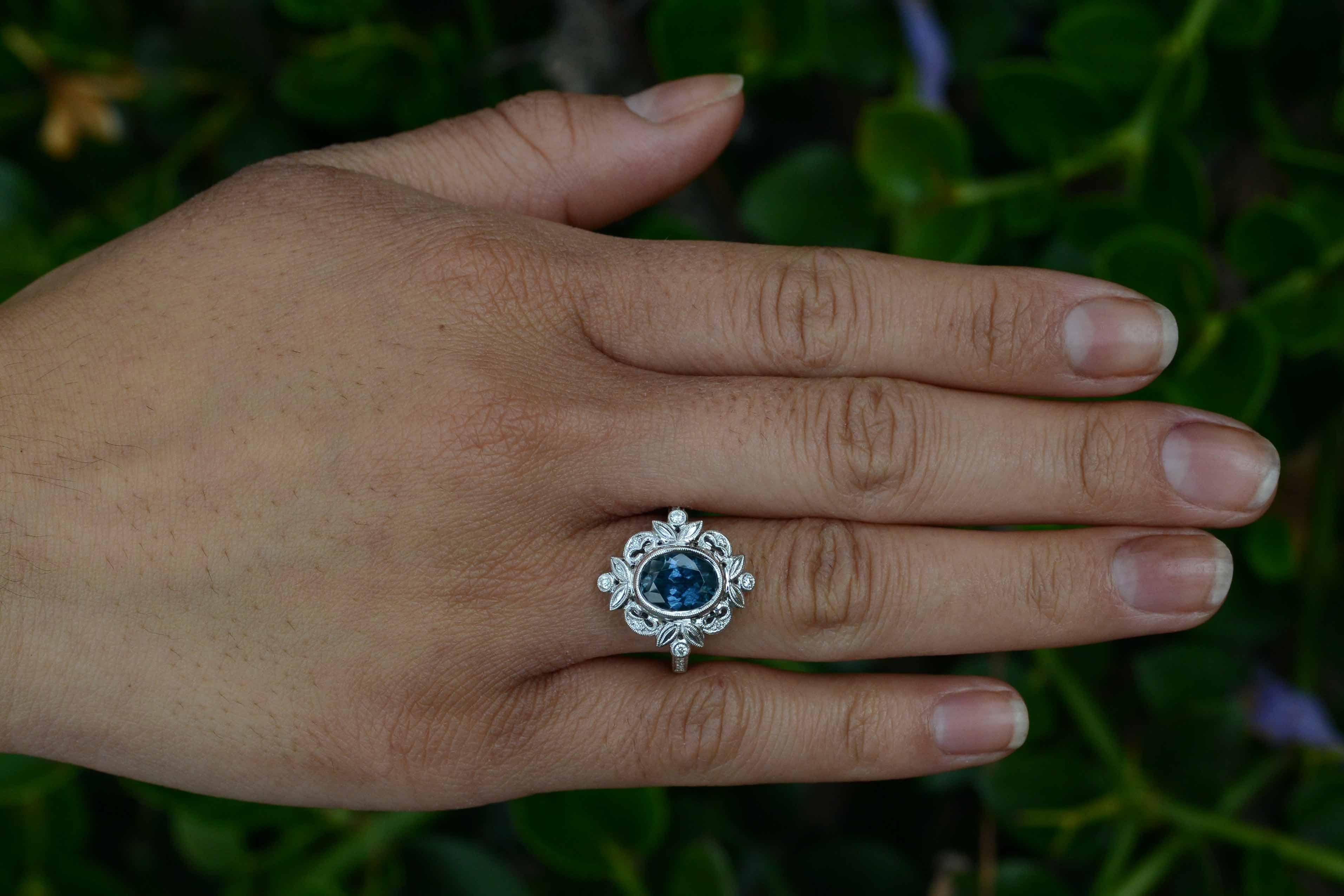 Centering on large, 2.79 oval Montana sapphire having an alluring, teal greenish-blue tone that is oh-so-velvety & rich, mounted in a most romantic Edwardian or Art Nouveau style floral diamond halo. This beautiful gem was discovered in a local