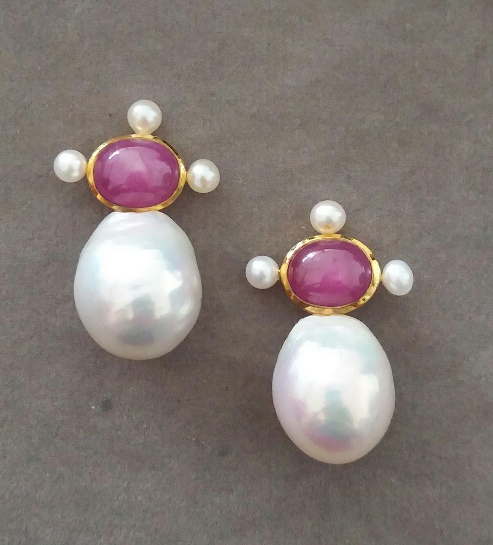 These elegant and handmade earrings have 2 Oval  Natural Ruby cabs measuring 8 x 10 mm set in a 14 Kt yellow gold bezel with 3 small round pearls of 3 mm on 3 sides at the top to which are suspended 2 very good luster White Pear Shape Baroque Pearls